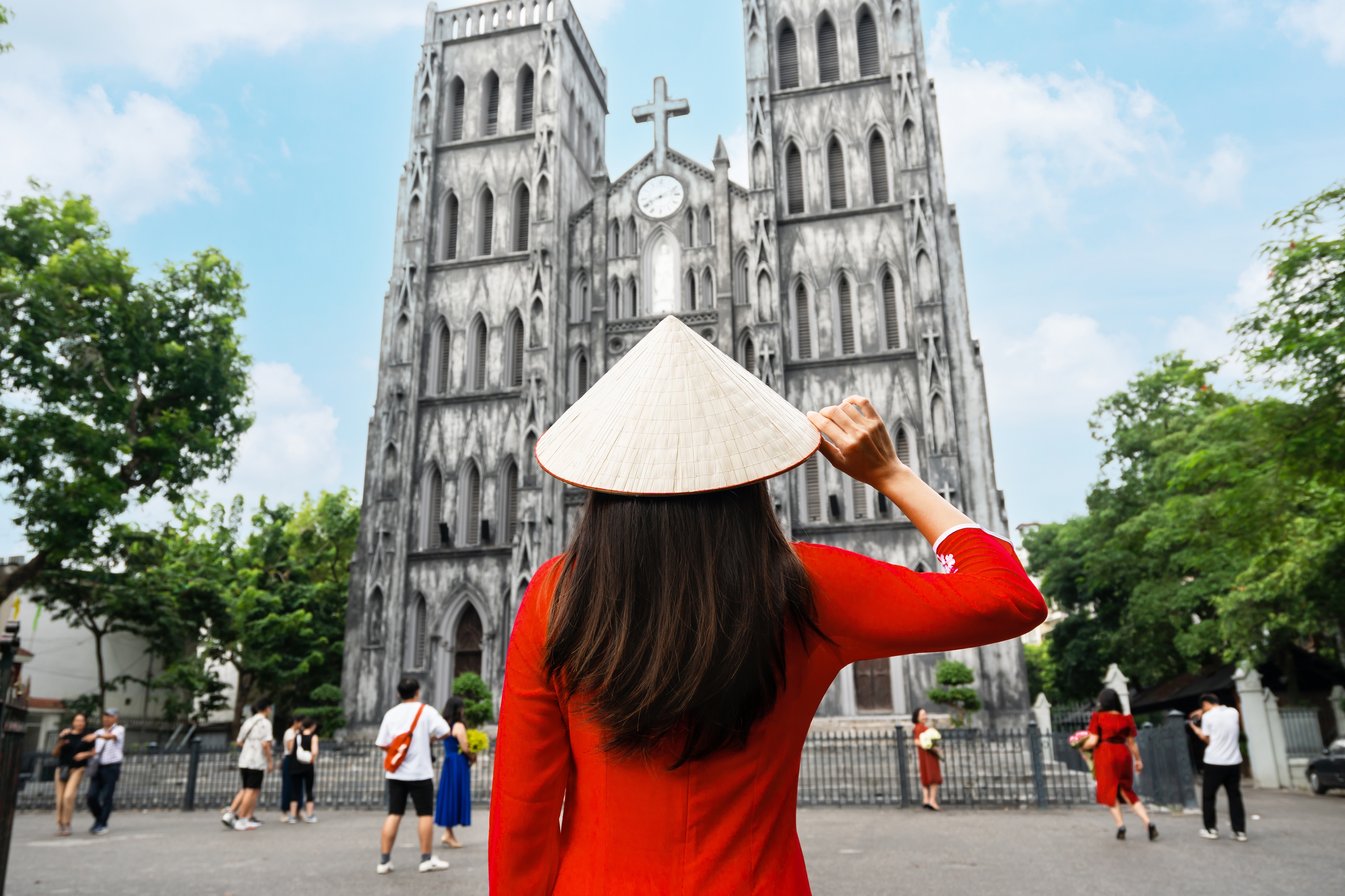 Young Asian woman tourist in Ao Dai (traditional Vietnamese dress) sightseeing at St Joseph's Cathedral church in Hanoi, Vietnam