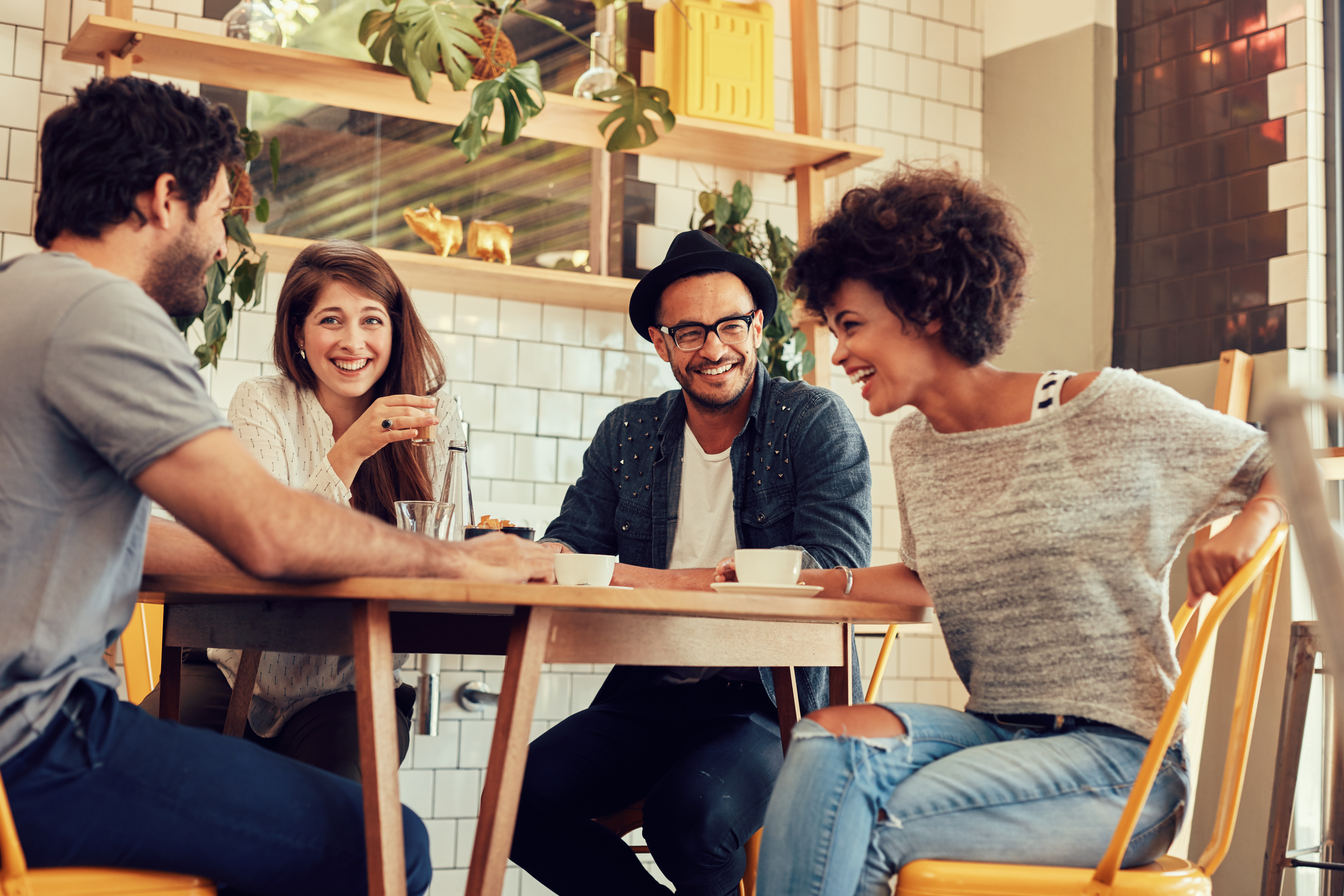 Portrait of cheerful young friends having fun while talking in a cafe. Group of young people meeting in a cafe.