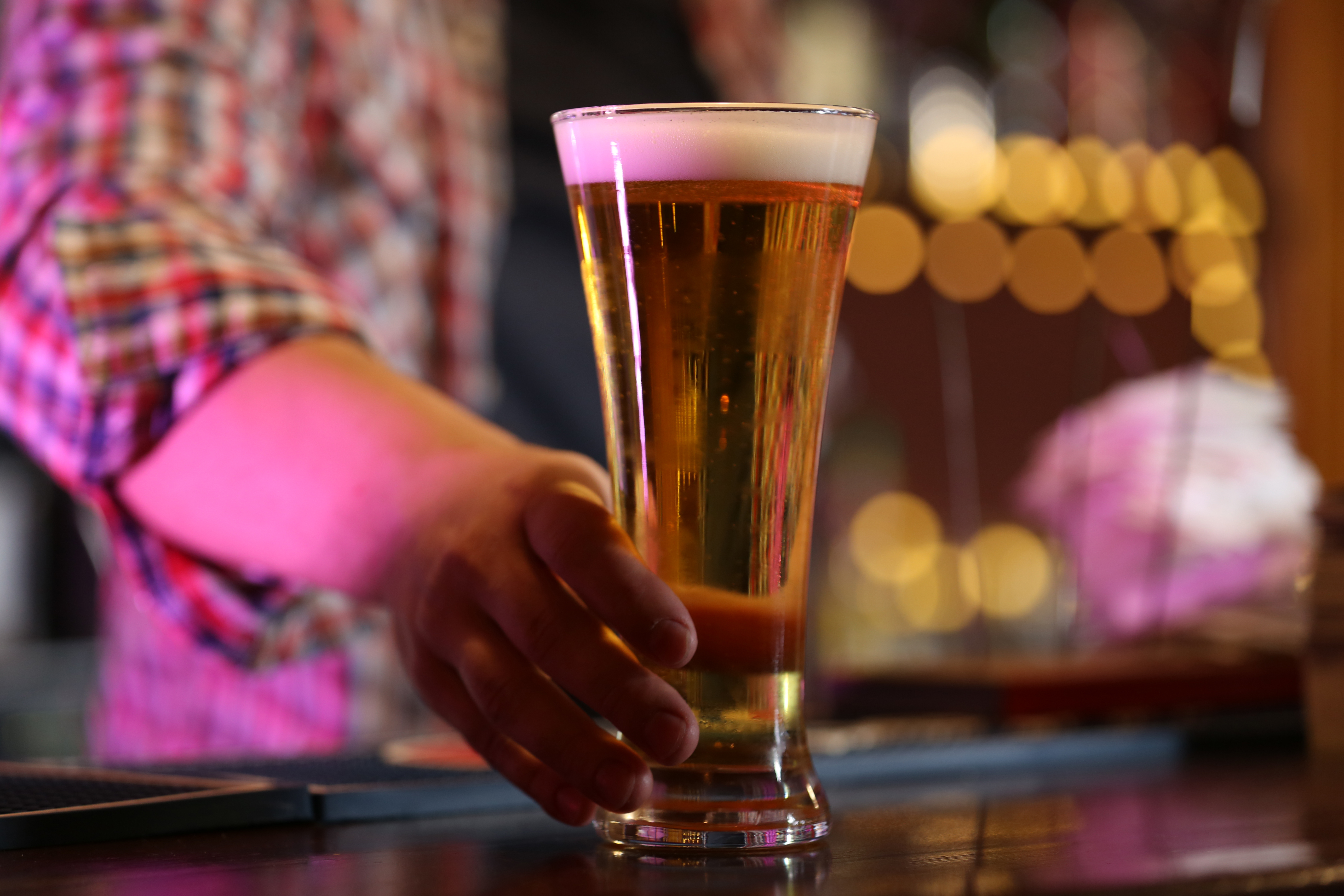 Bartender holding beer glass at workplace