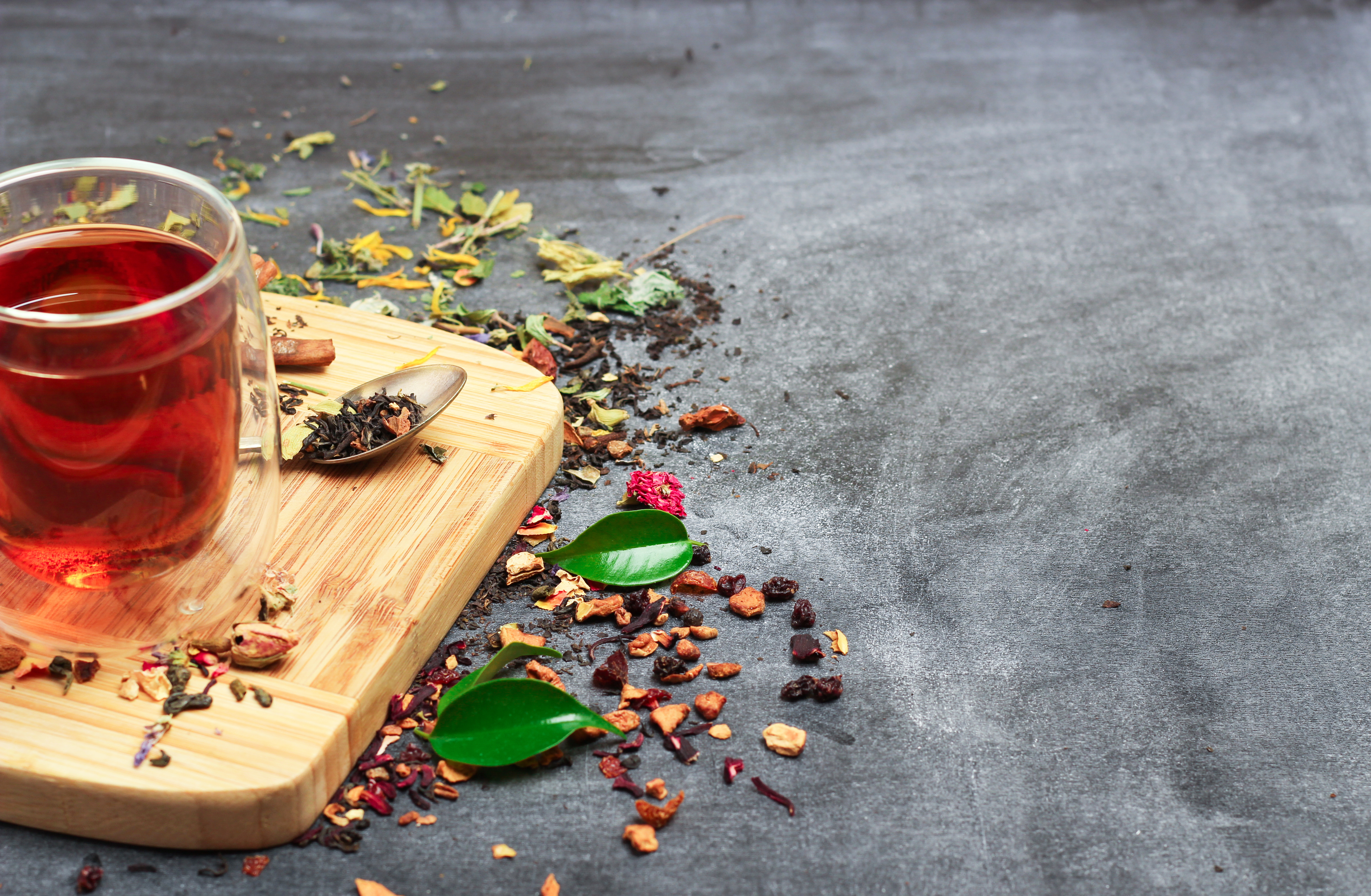 Still life, food and drink concept. Various kinds of tea with a glass of tea on a black chalkboard. Selective focus, copy space background.