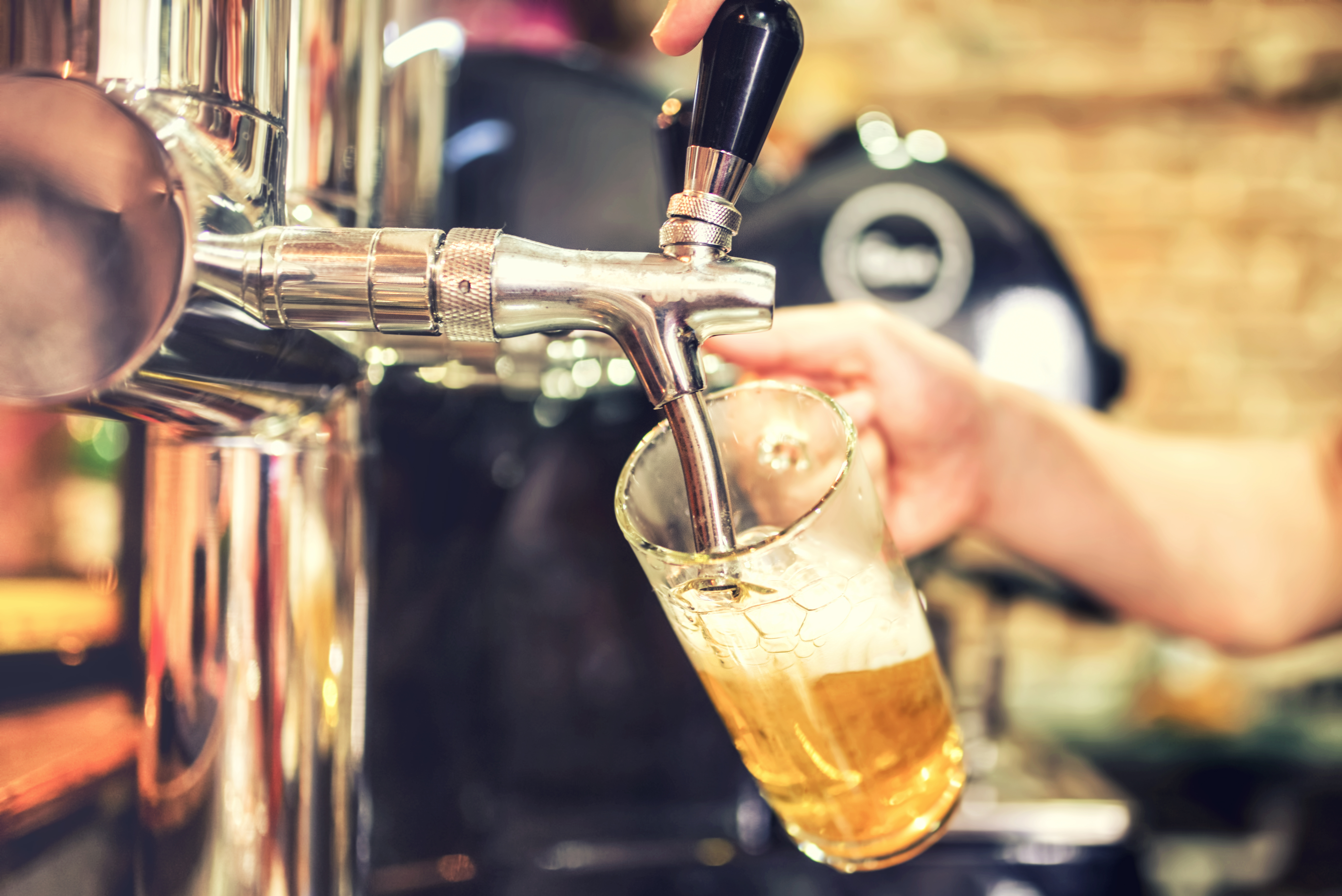 Man drawing a beer from tap on a kegerator in pub or inn