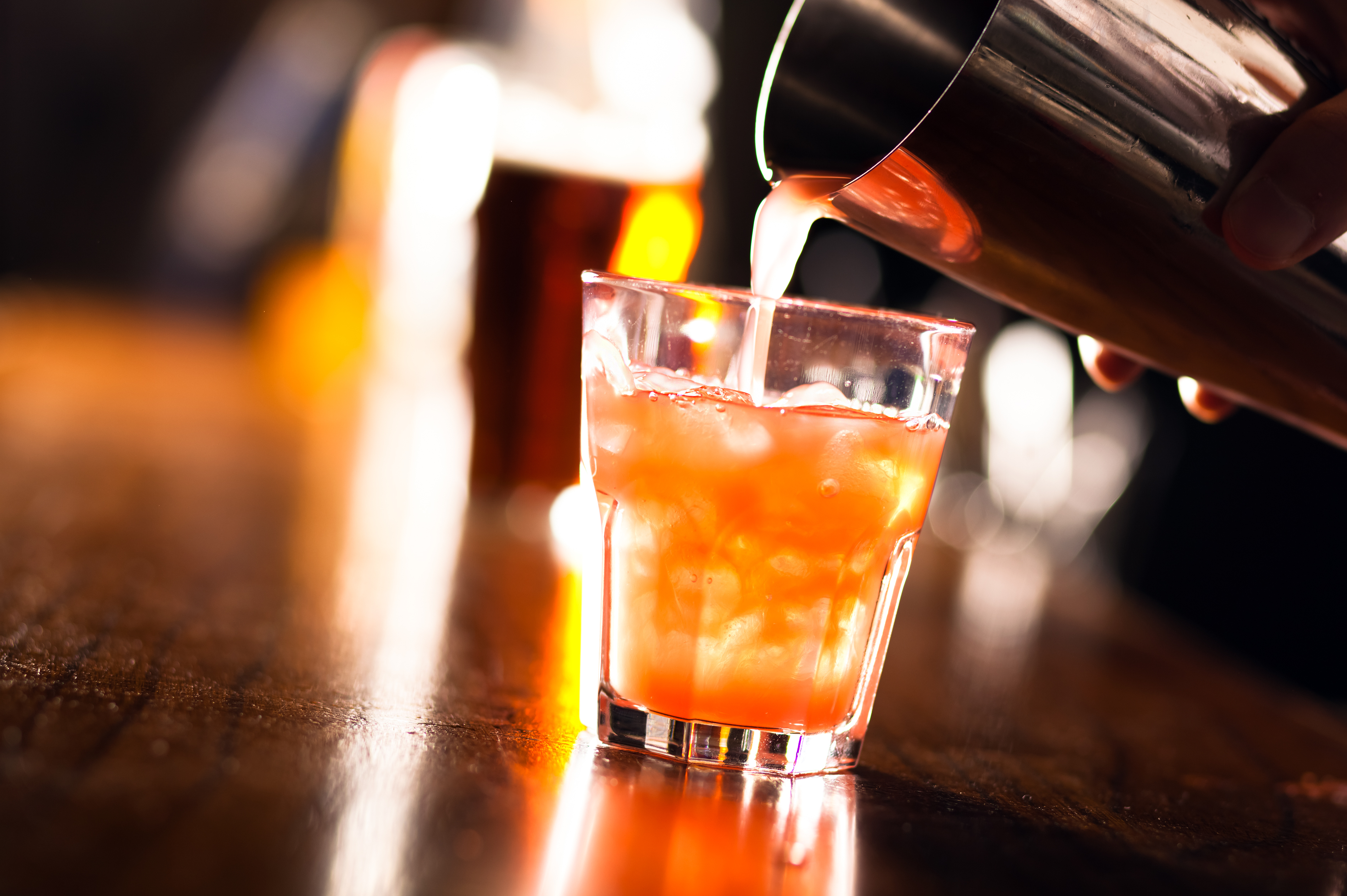 Barman pouring a cocktail into a glass
