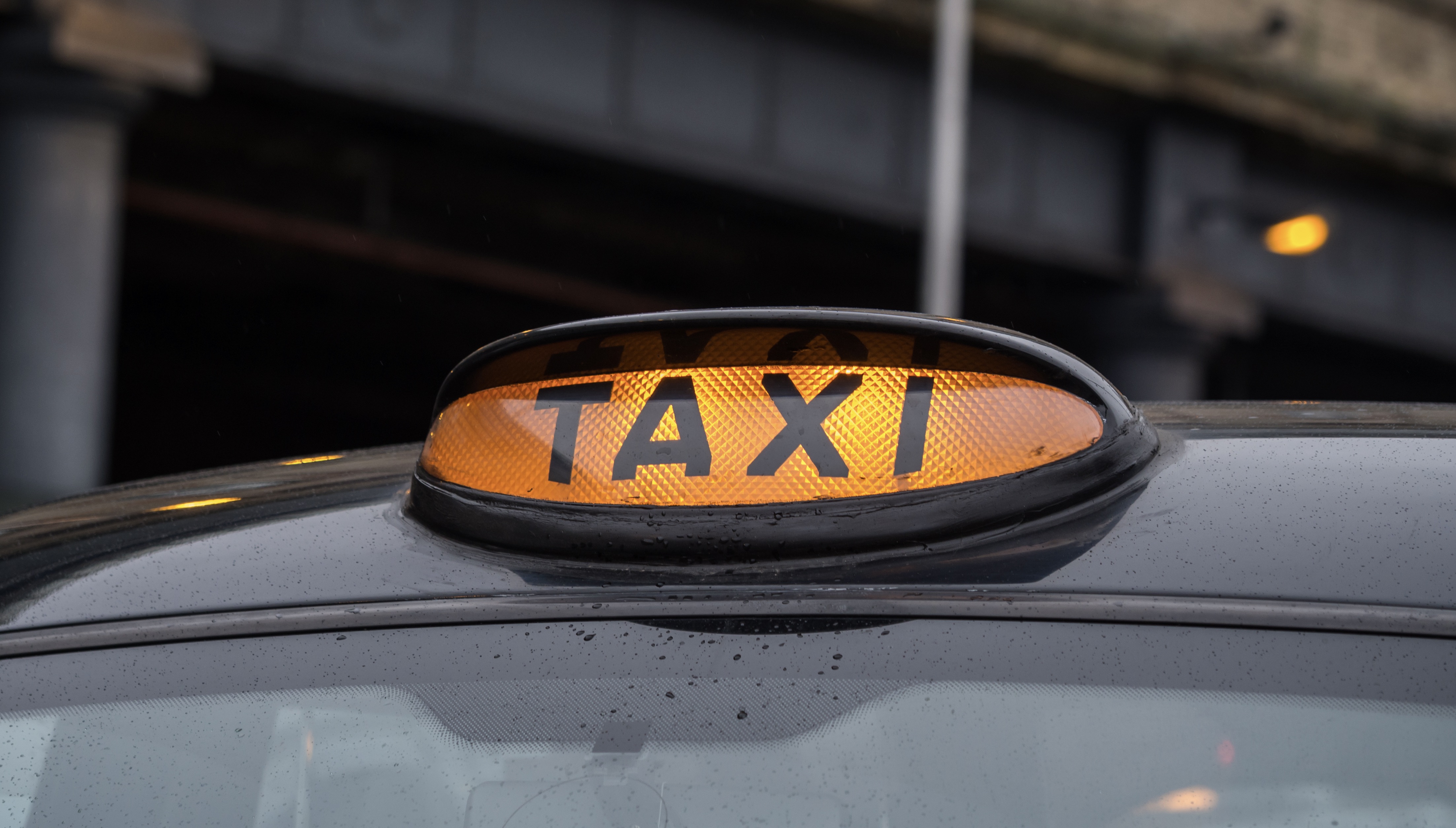 Illuminated yellow taxi sign on a typical old style black taxi in Manchester, Great Britain