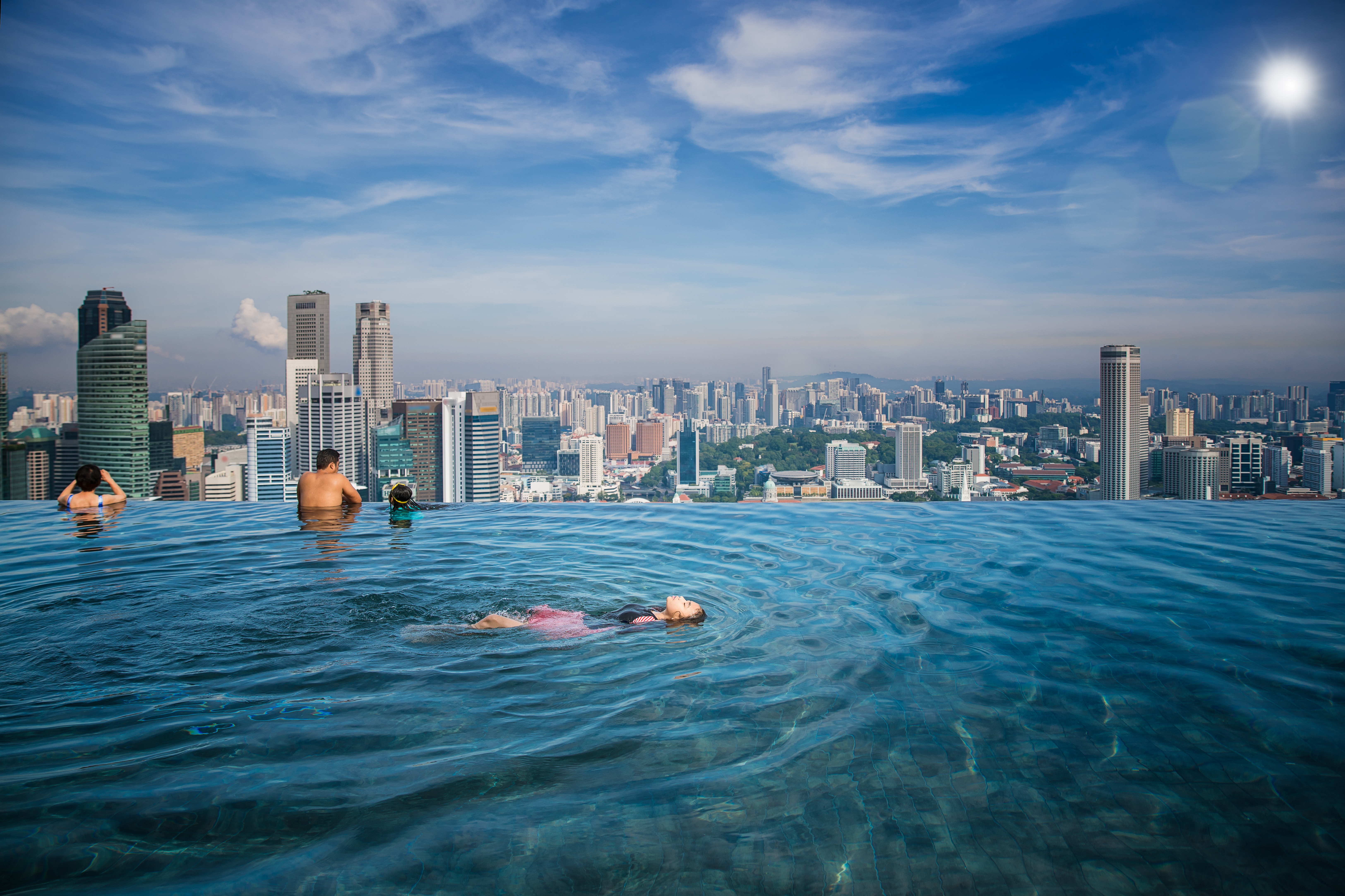 Asian girl swim in swimming pool on the roof top of hotel in Singapore city, Singapore and summer concept