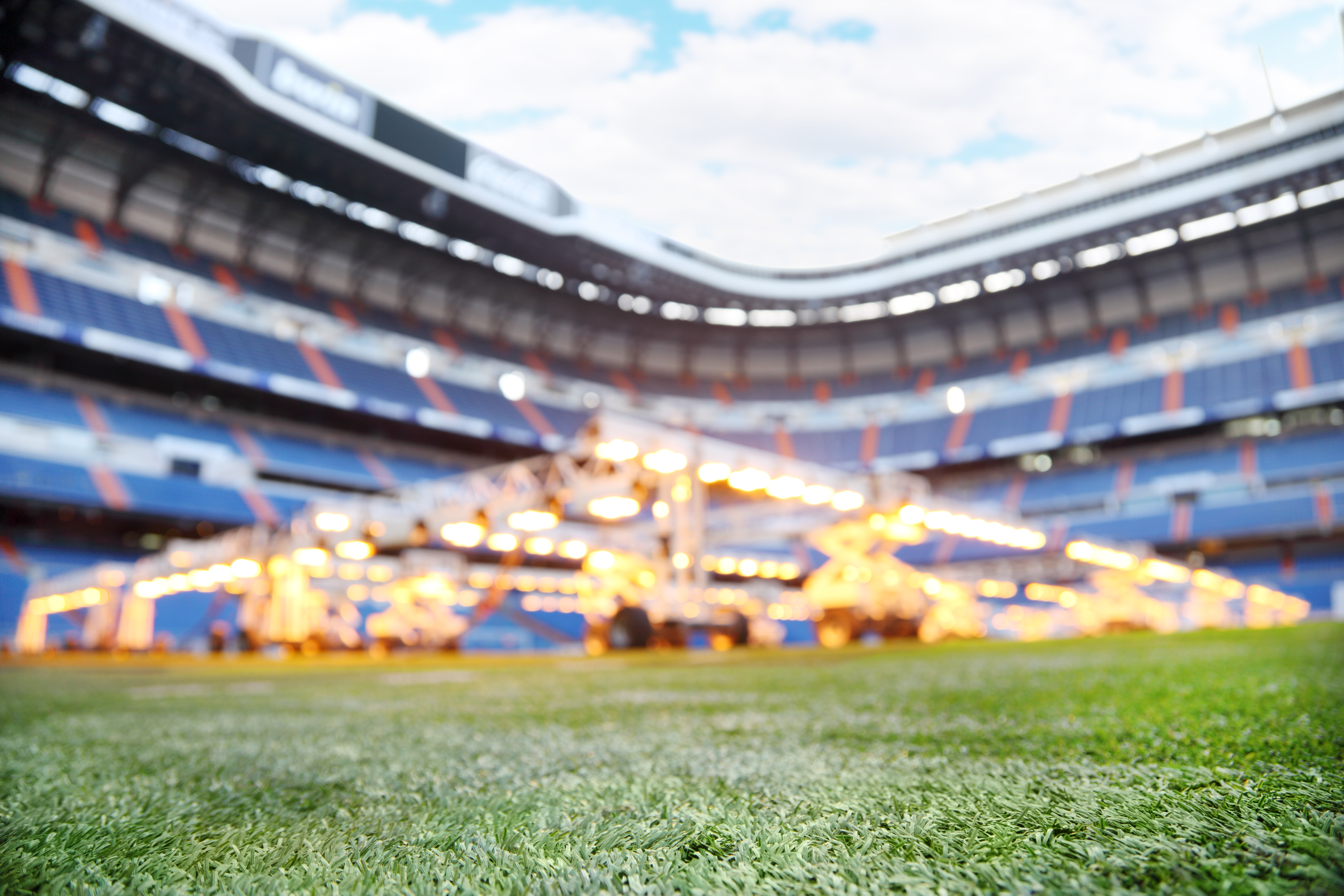 Lawn and lighting system for growing grass at empty outdoor football stadium. Focus on grass.