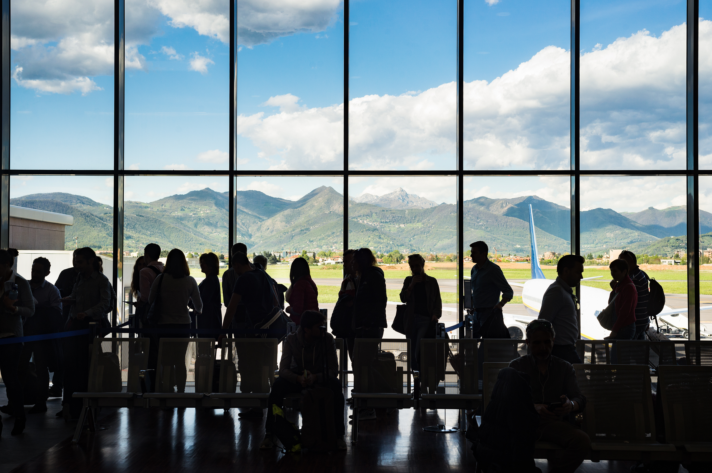 Silhouette crowd people waiting for airplane in airport terminal with mountain background at Milan Bergamo, Italy