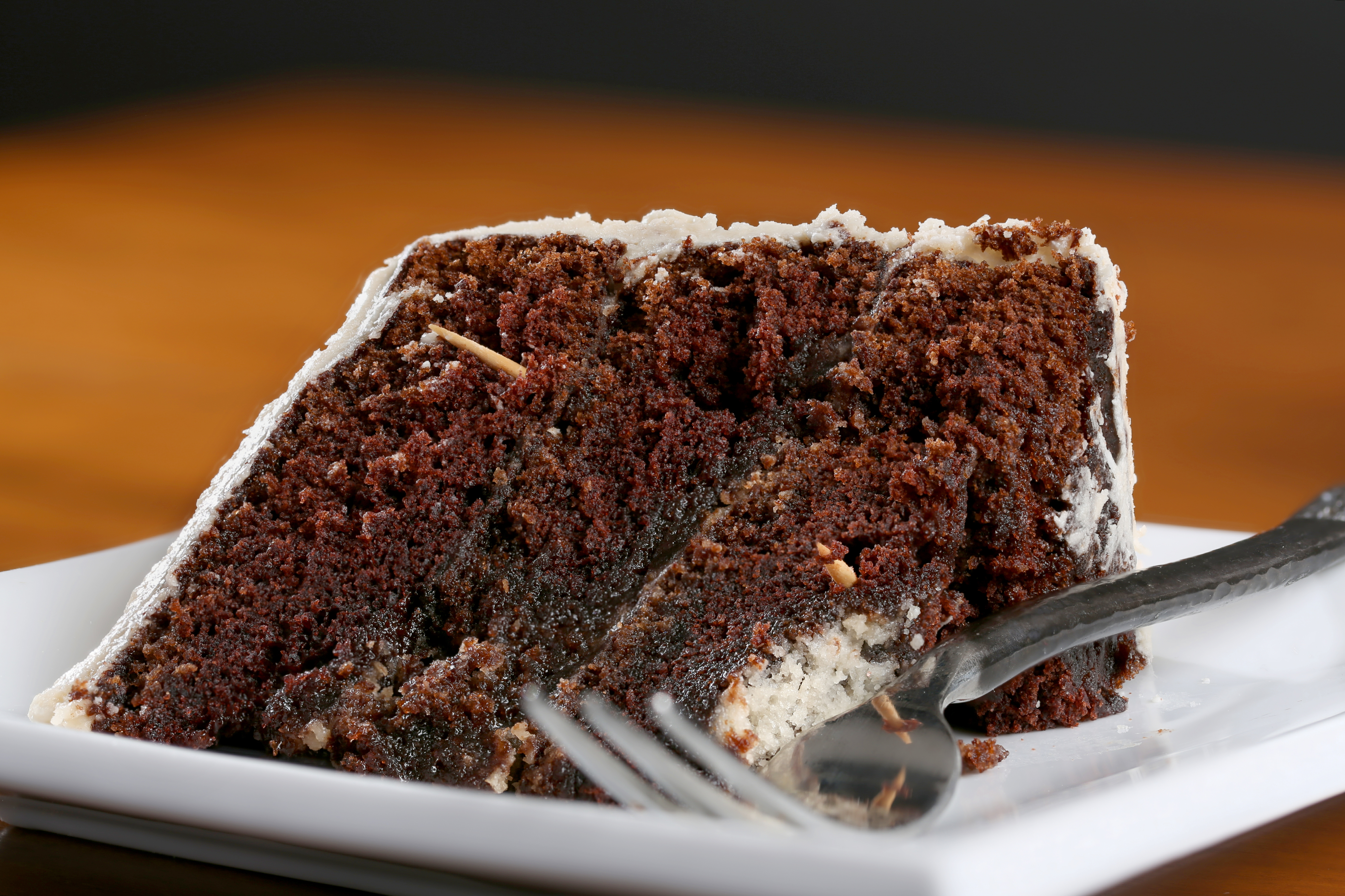 A slice of rich moist chocolate cake on a white plate with layers