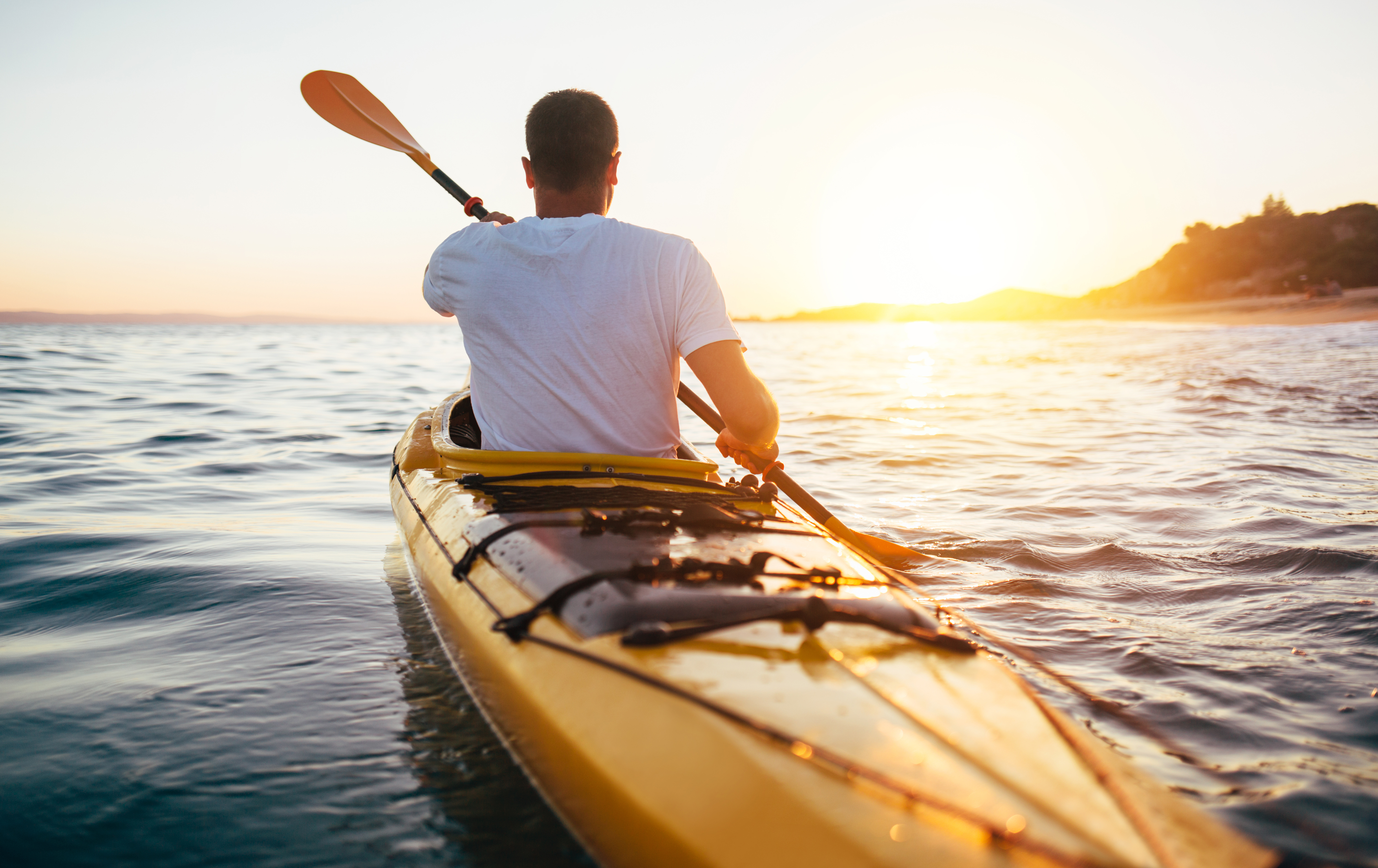 Rear view of kayaker man paddle kayak at sunset sea. Kayaking, canoeing, paddling