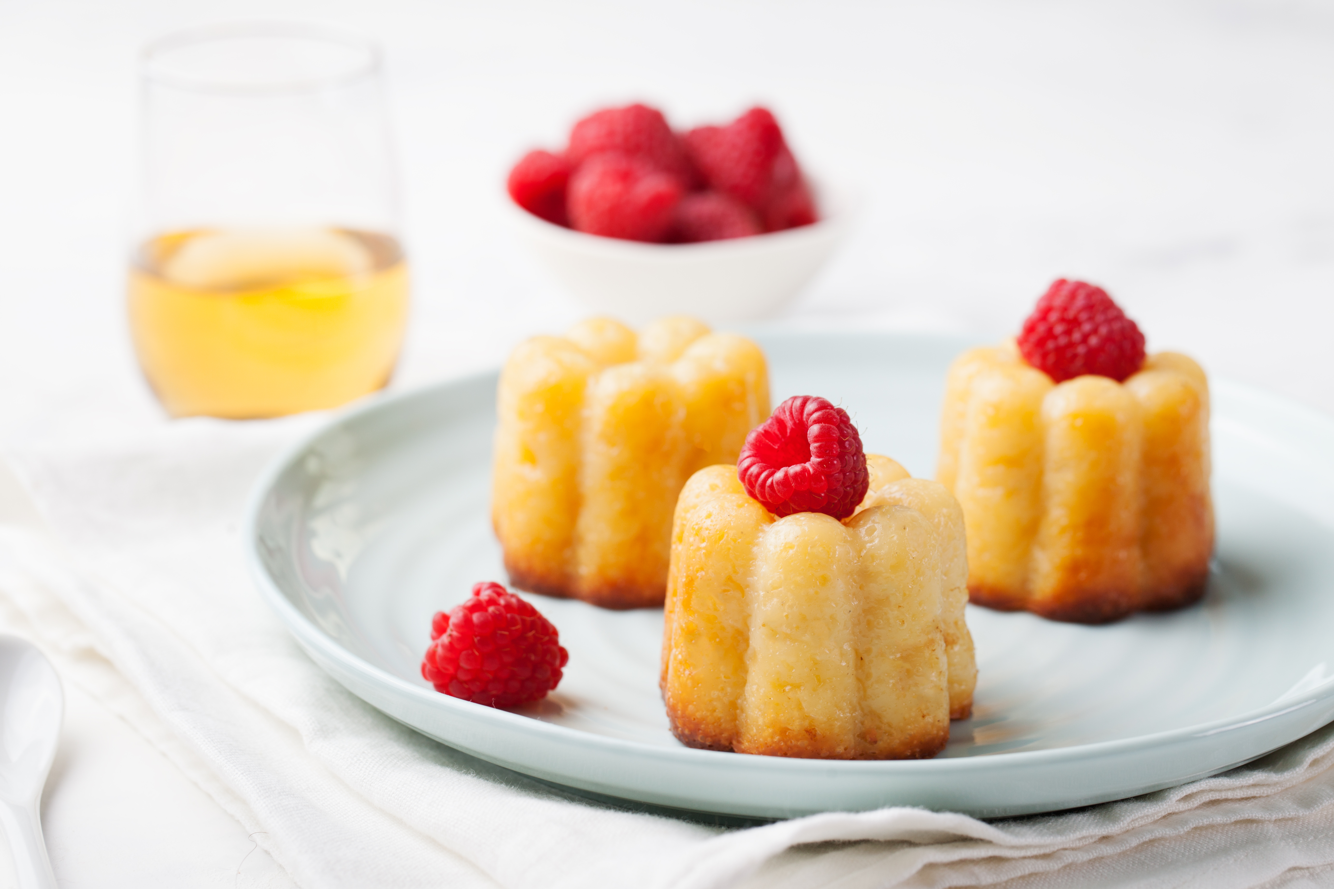 French dessert, cakes, caneles, rum baba with fresh raspberry and dessert wine on a white background