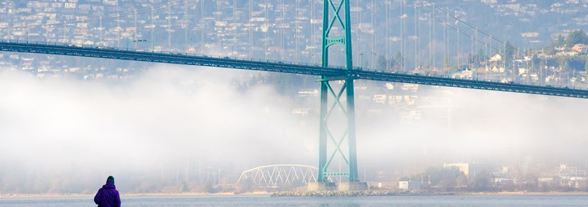A foggy winter day in Vancouver, British Columbia, Canada, as seen from the seawall in Stanley Park, with the Lions Gate Bridge and North Shore Mountains in the background.