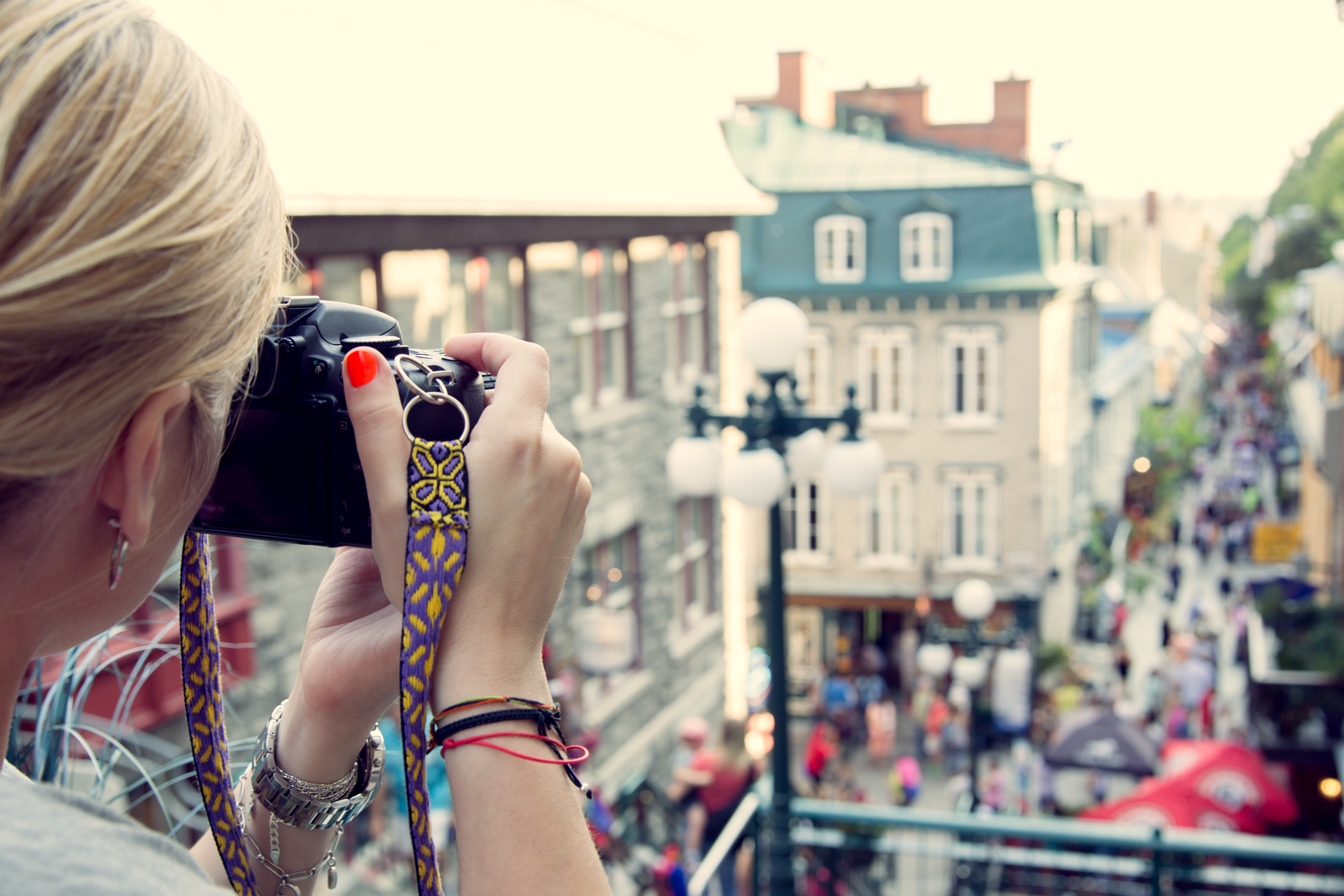 Young woman taking pictures on the busy rue Petit Champlain in Quebec City, Canada. North American, adventure, travel vacation, photography, outdoors and life style concept