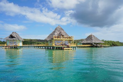 Tropical resort over water with thatched roof bungalow, Caribbean sea - Seaphotoart / Shutterstock.com