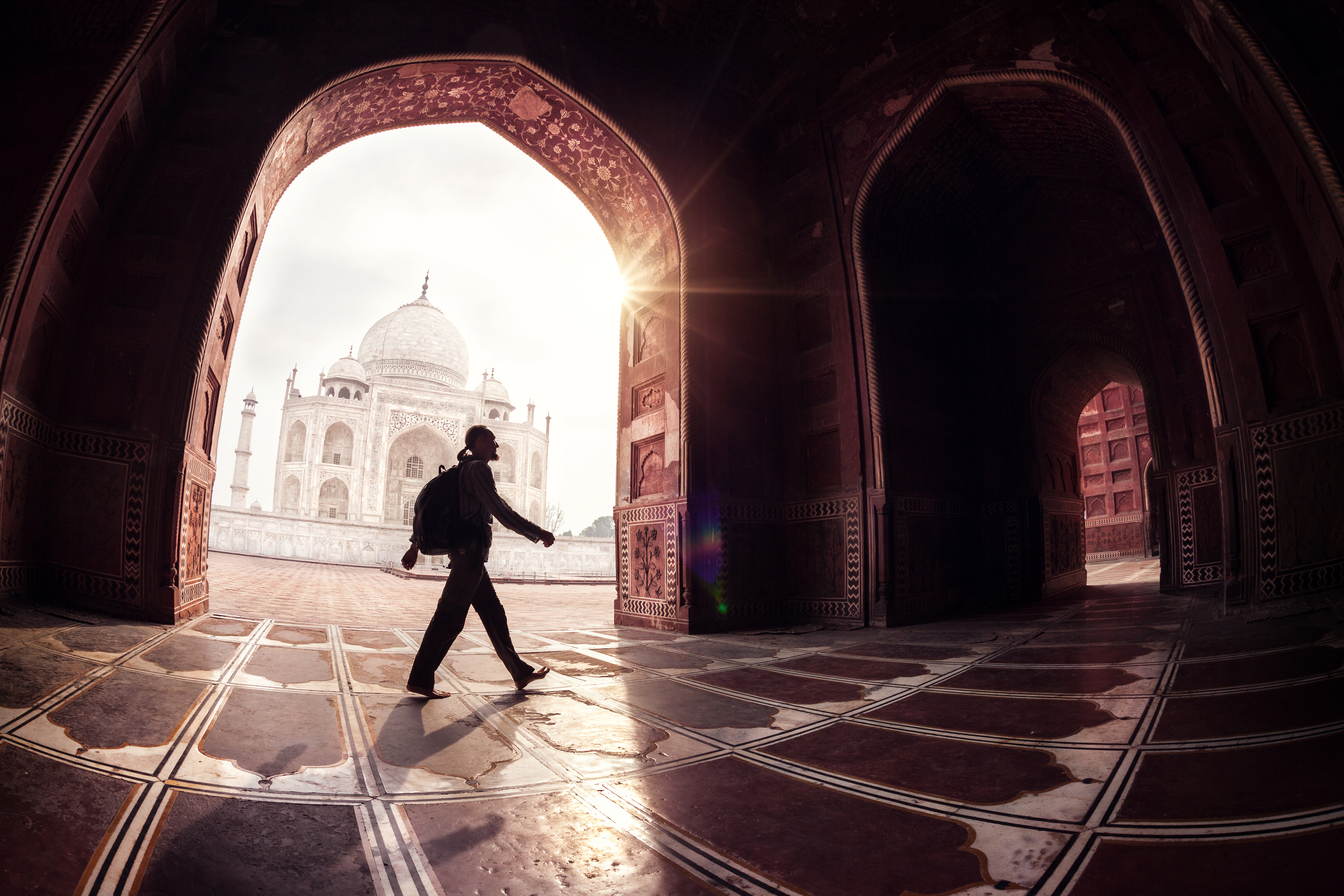 Tourist with backpack walking in the mosque arch near Taj Mahal in Agra, Uttar Pradesh, India