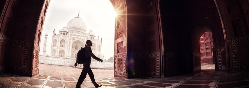 Tourist with backpack walking in the mosque arch near Taj Mahal in Agra, Uttar Pradesh, India
