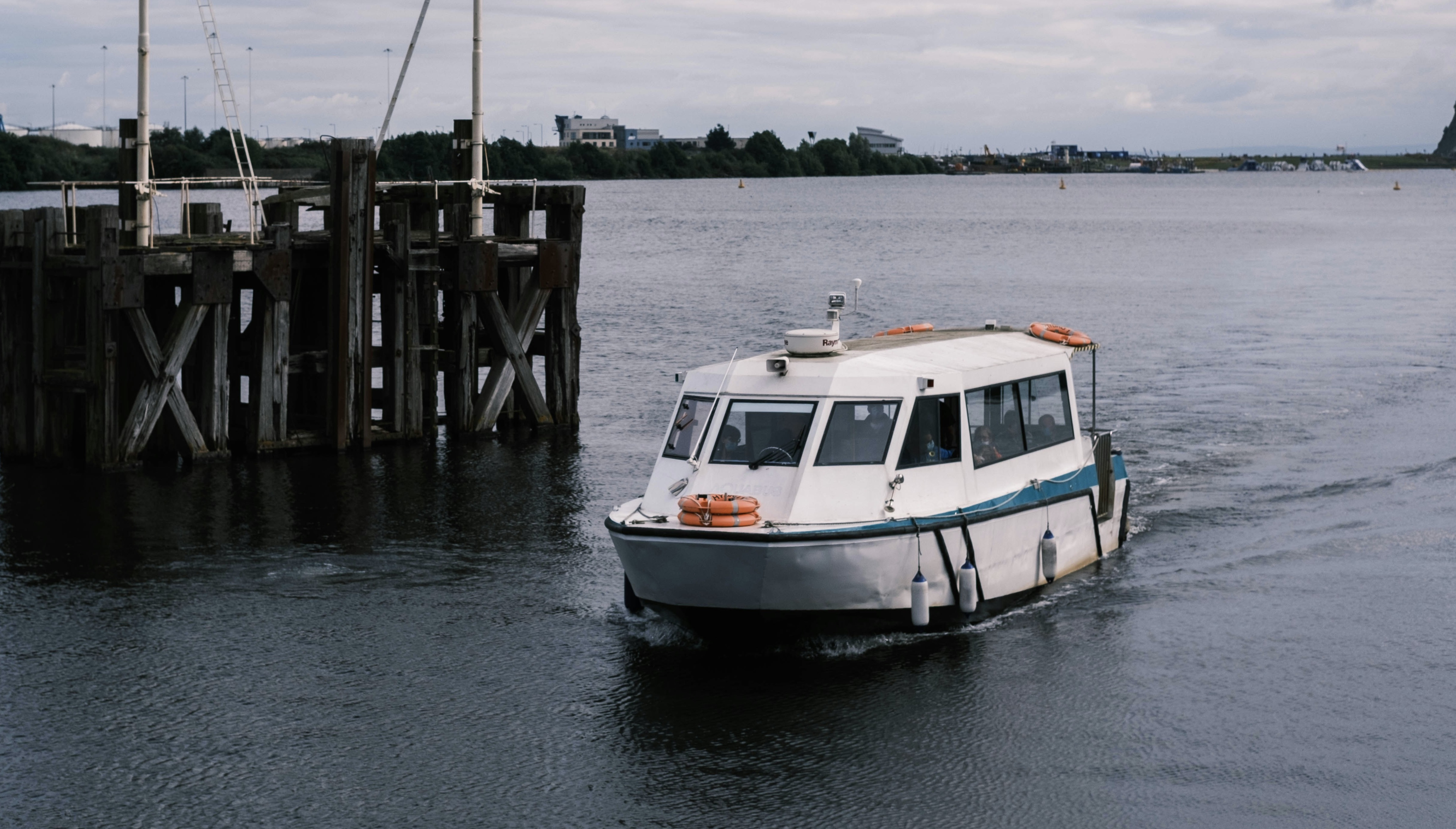 water bus floats by a wooden bollard in Cardiff Bay, Wales