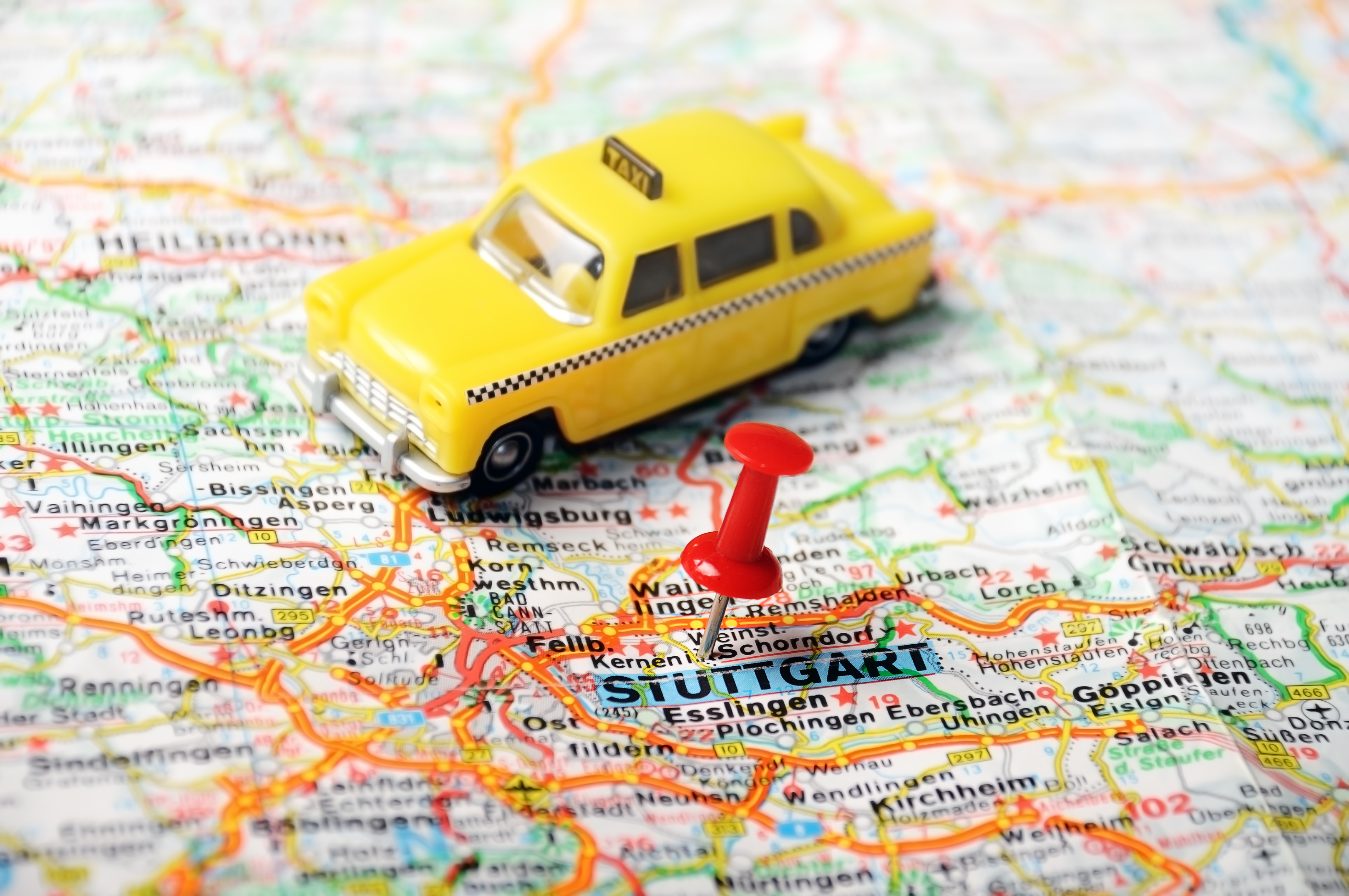 Close up of Stuttgart map with red pin and a taxi - Travel concept