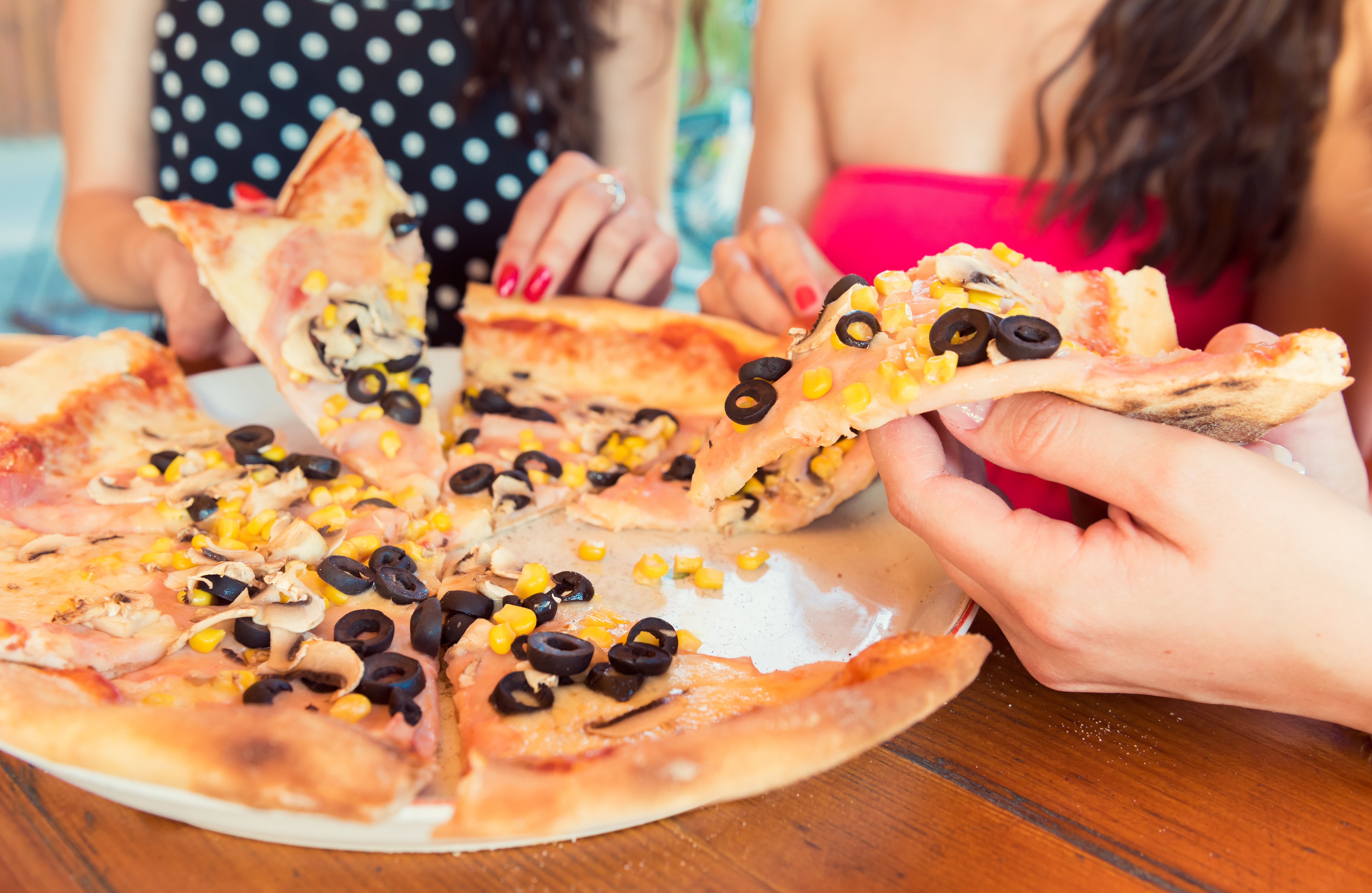 Anonymous female friends sharing a pizza
