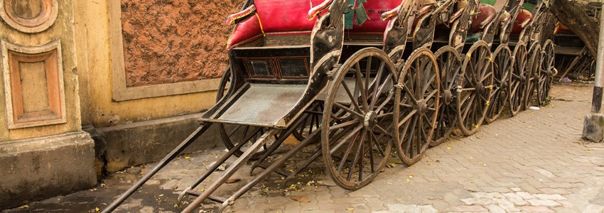 Traditional hand pulled Indian rickshaws parked together in front of a old building in Kolkata