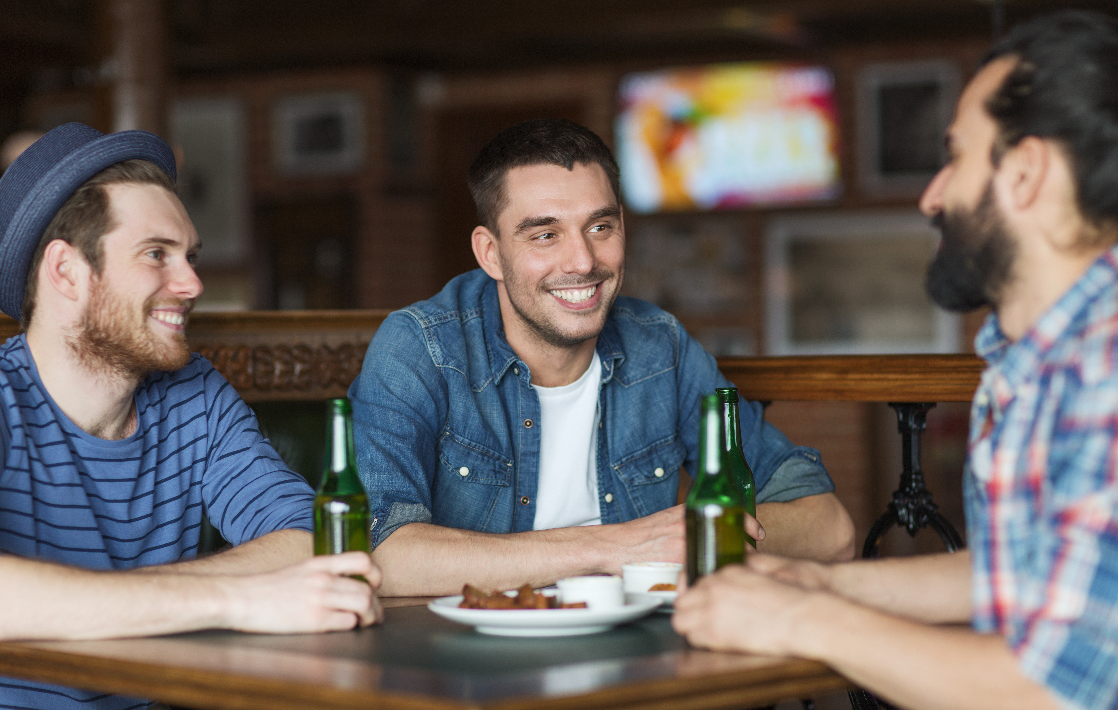 male friends drinking bottled beer and talking at a pub