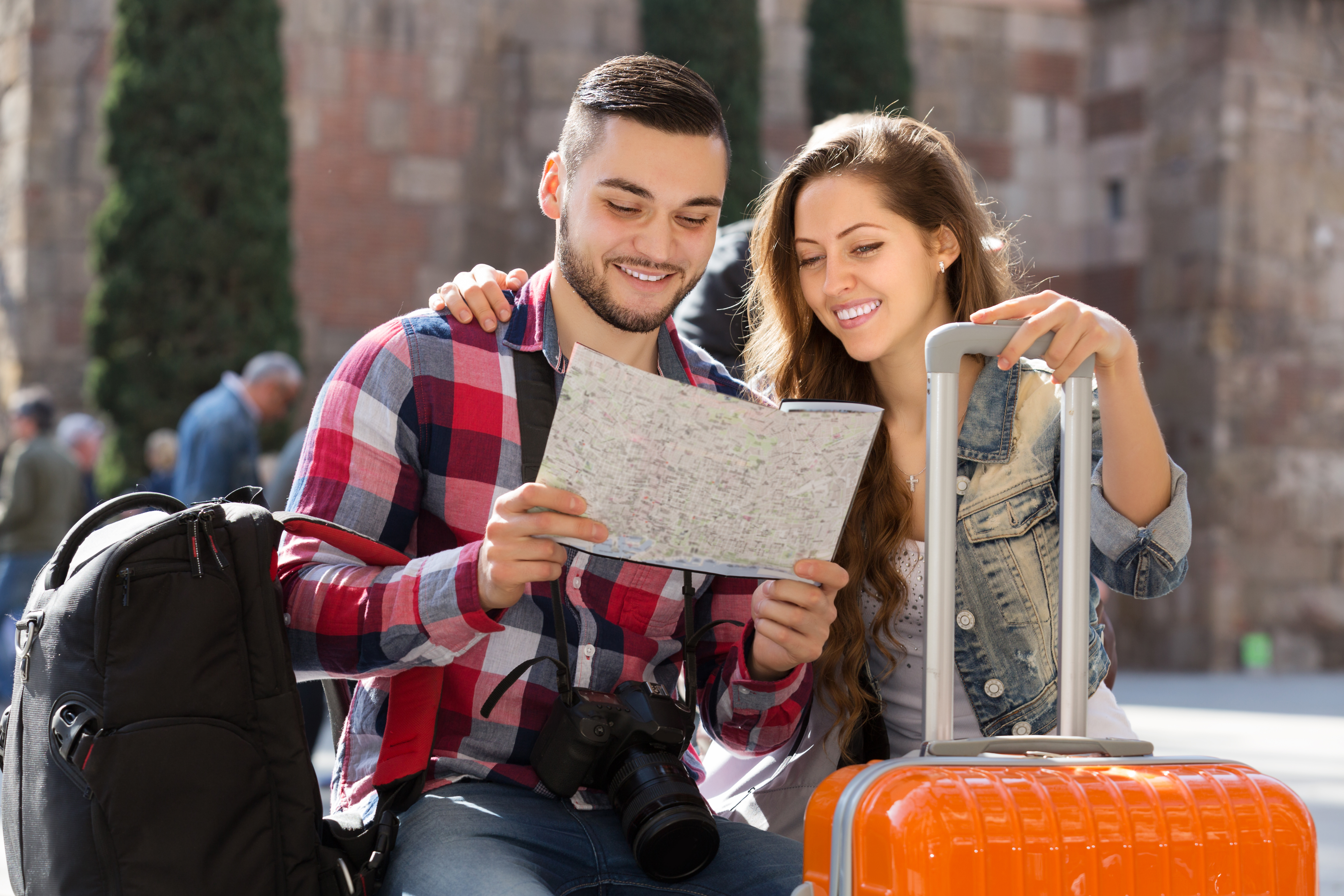 Happy couple in casual clothes with trunk and backpack outdoor