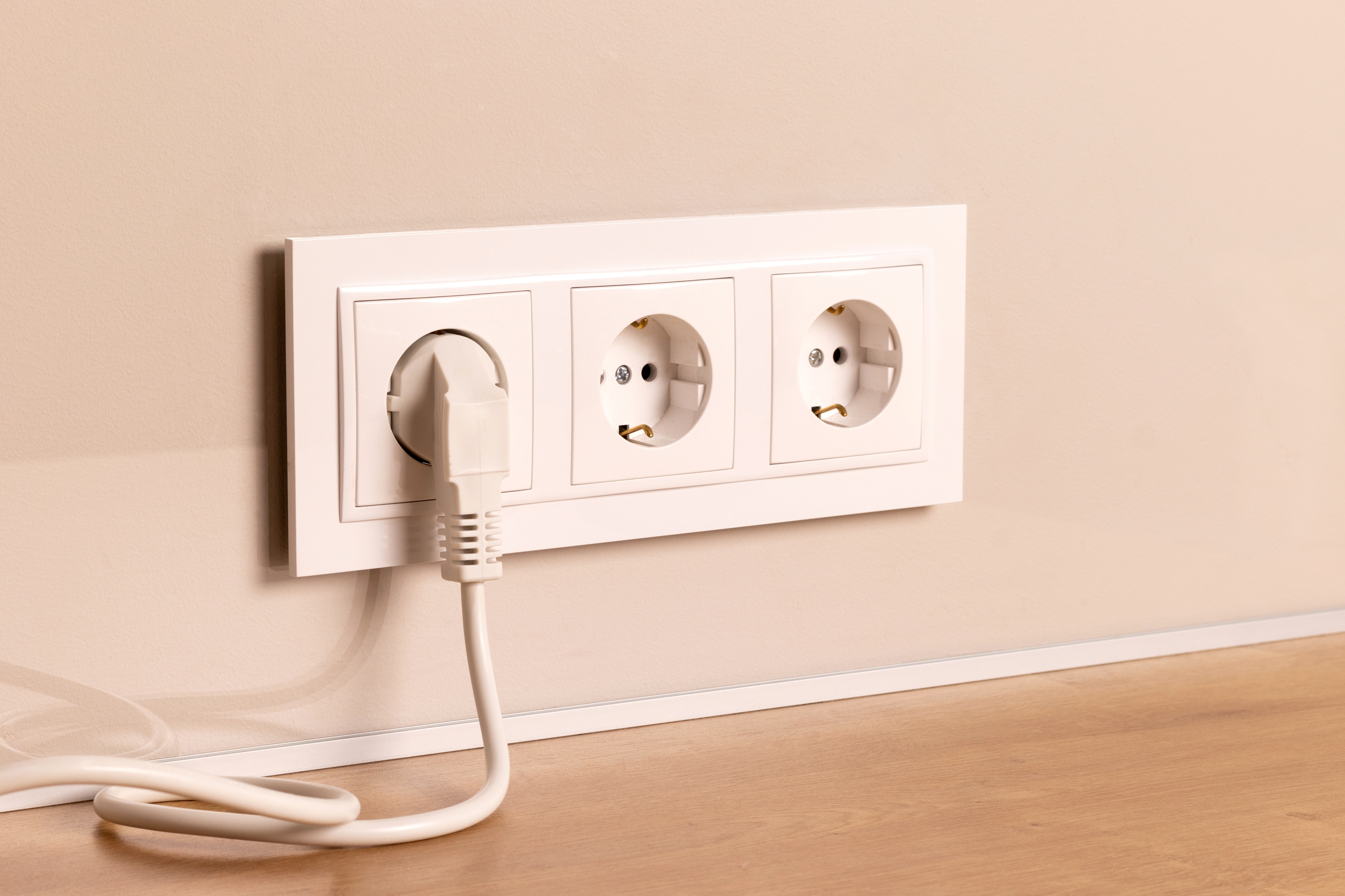 white European electrical outlets with plug inserted into it on modern beige wall