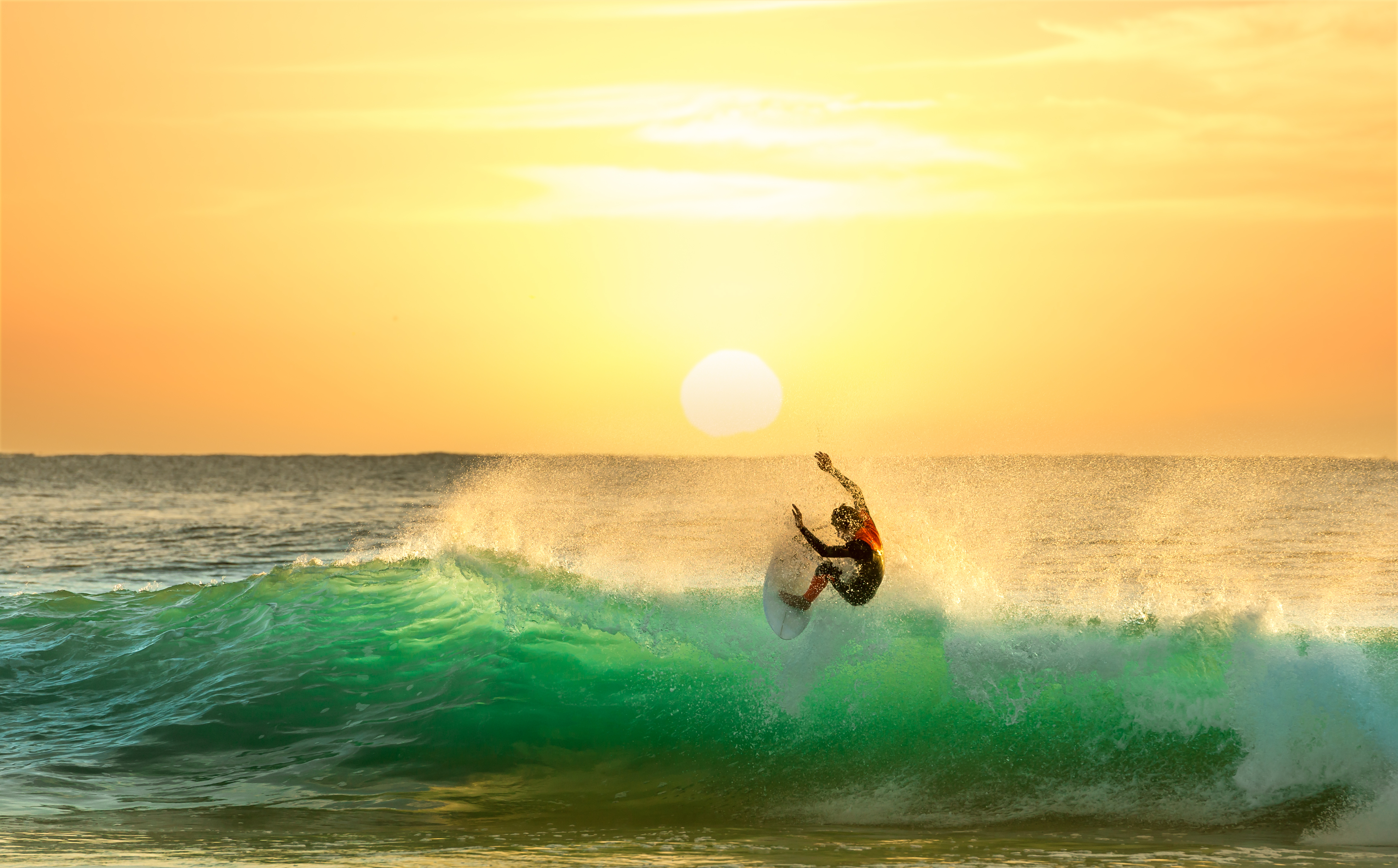 Surfing on a Green Wave with Sun Rising in the Background