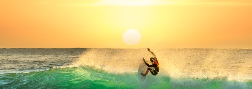 Surfing on a Green Wave with Sun Rising in the Background