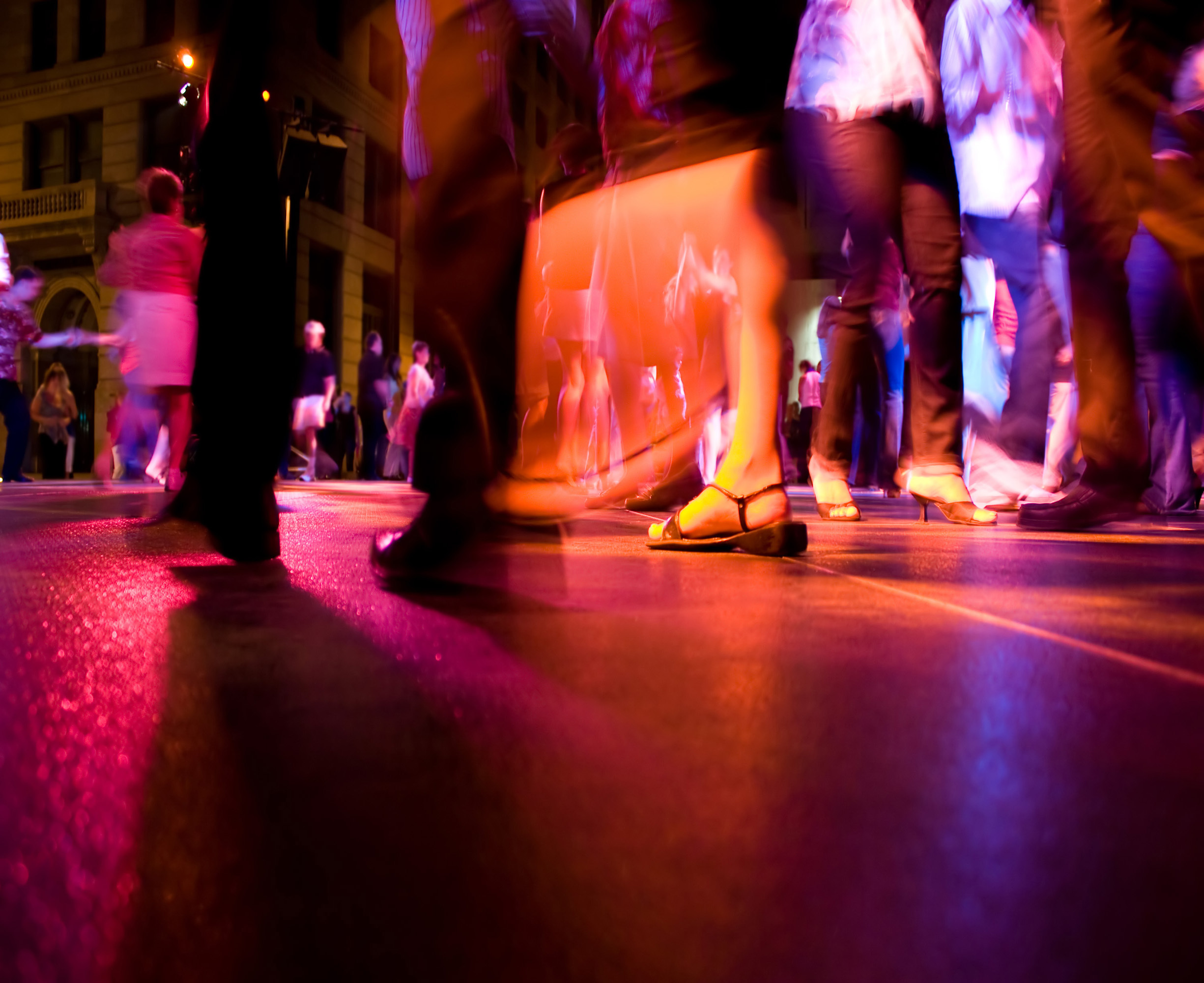 A low shot of the dance floor with people dancing under the colorful lights