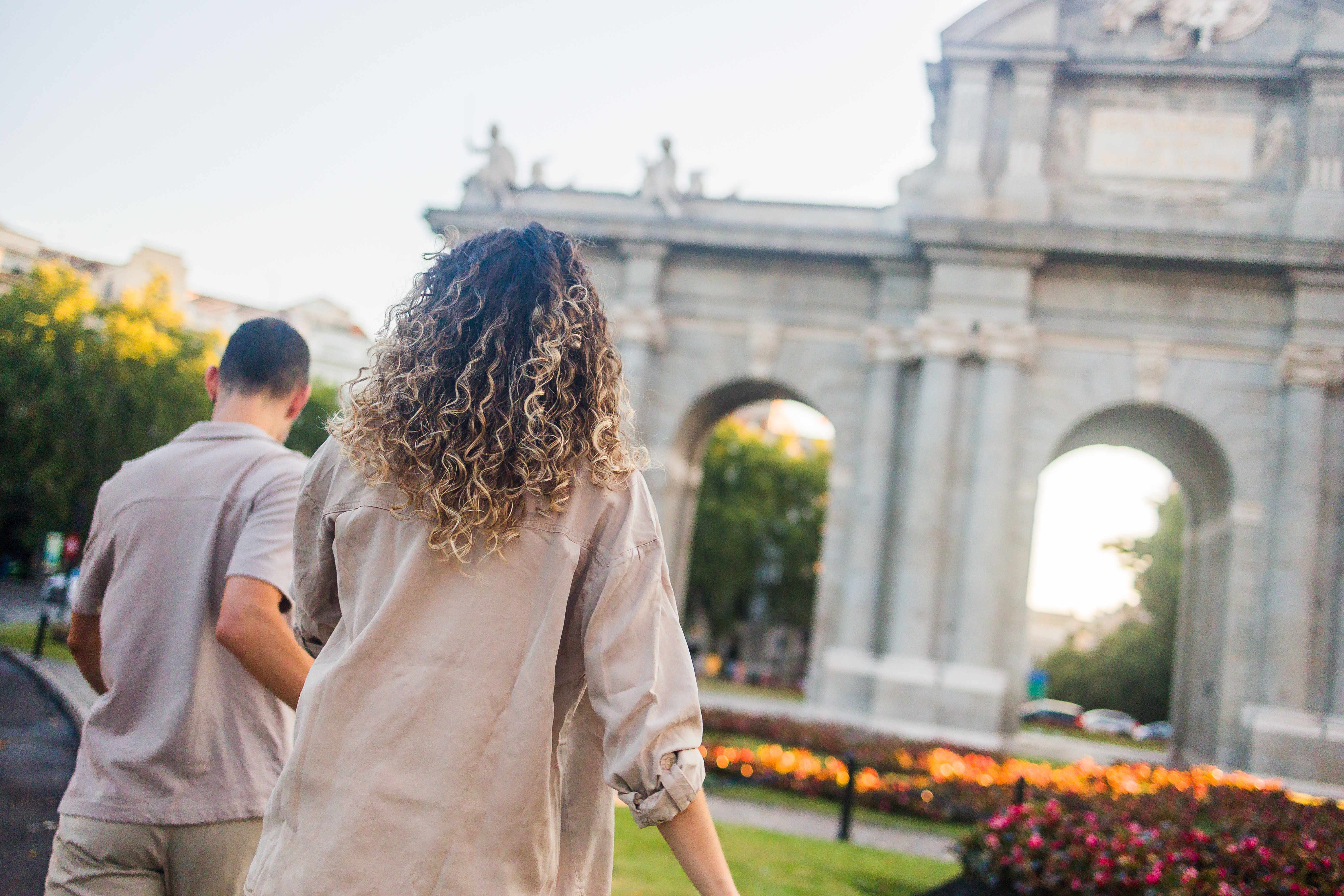 Couple walking towards Puerta de Alcala in Madrid, Spain