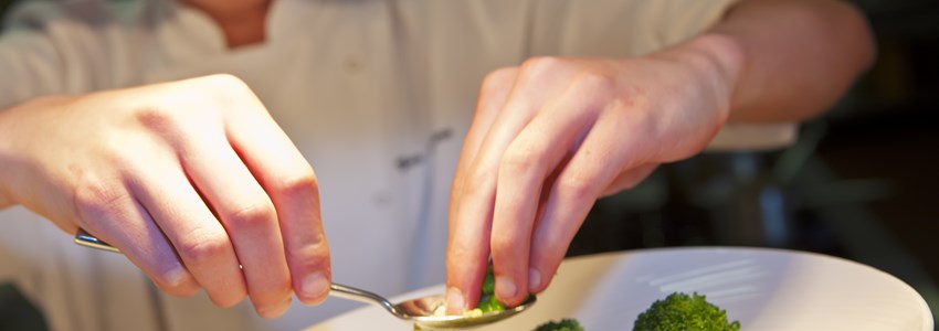 Closeup of chef adding finishing touch on his dish