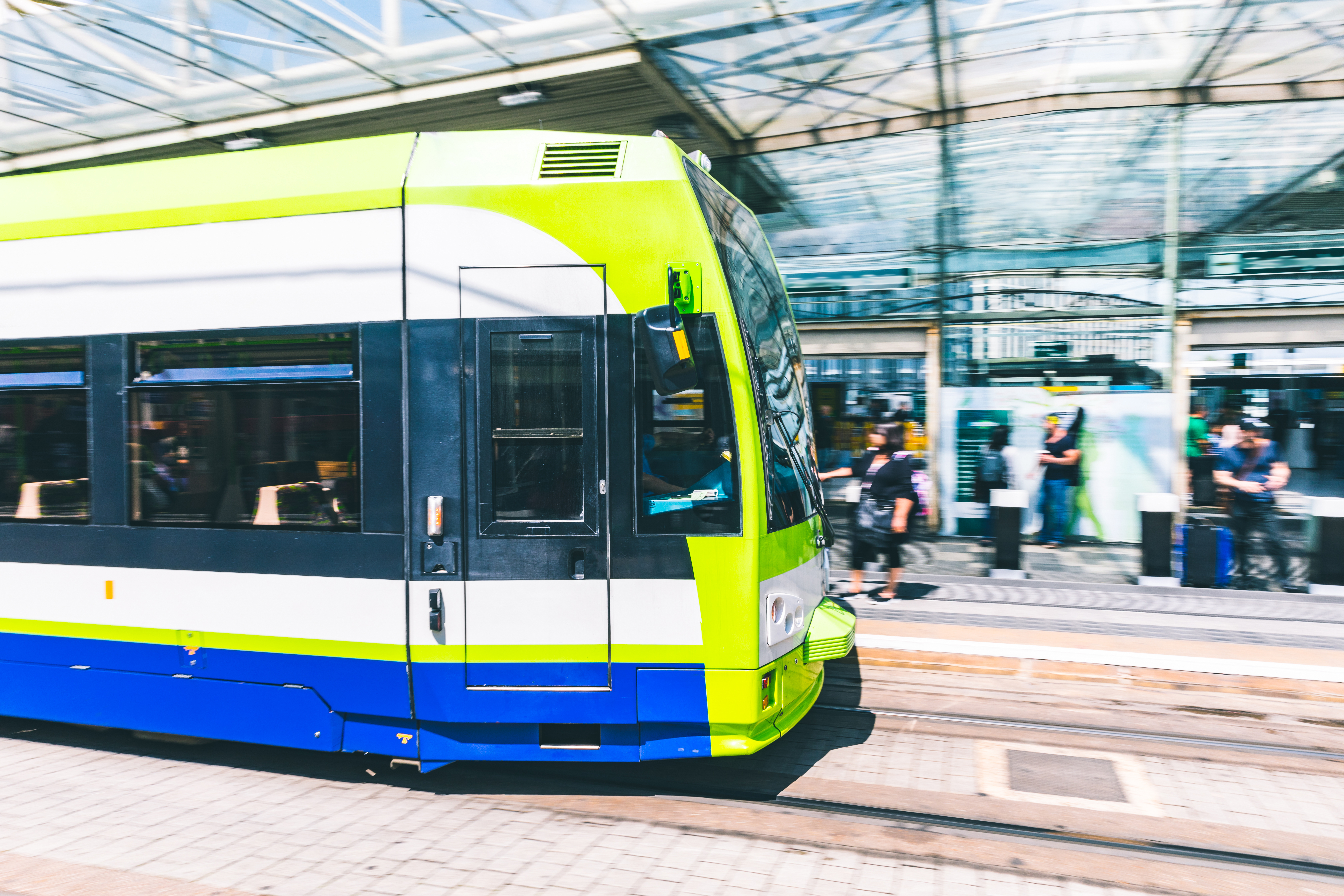 Blurred tram approaching or leaving the station. Urban scene, public transport mode, people waiting on the platform. City life, commuting and transportation concepts