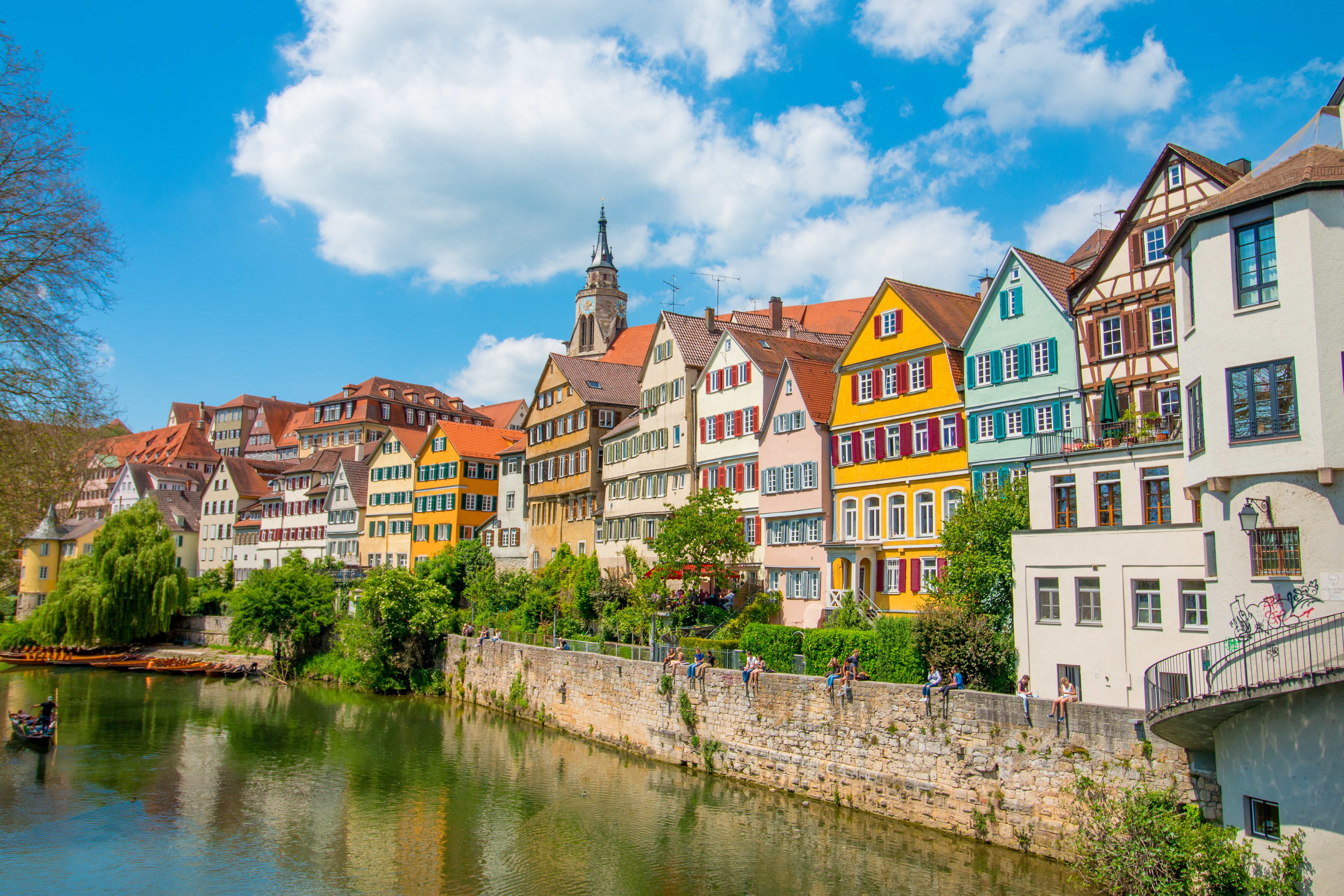 Tuebingen in the Stuttgart city ,Germany Colorful house in riverside and blue sky. Beautiful old city in Europe.People sitting on the wall. Boats wooden moored at dock.