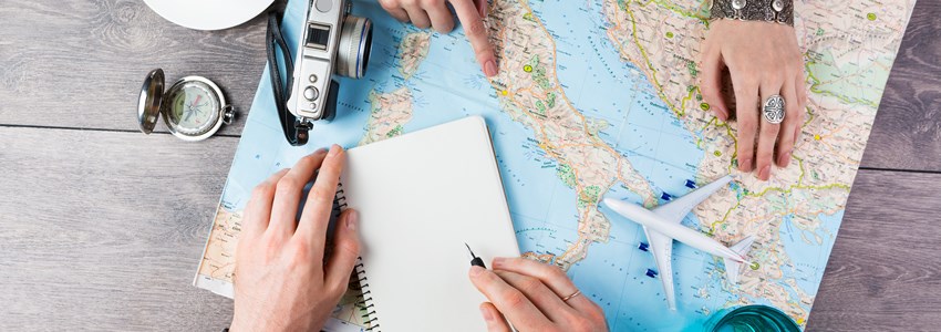 Two young people together planning trip to Europe. Top view. empty white space in notebook where you can place your text or advertisement. Romantic travel