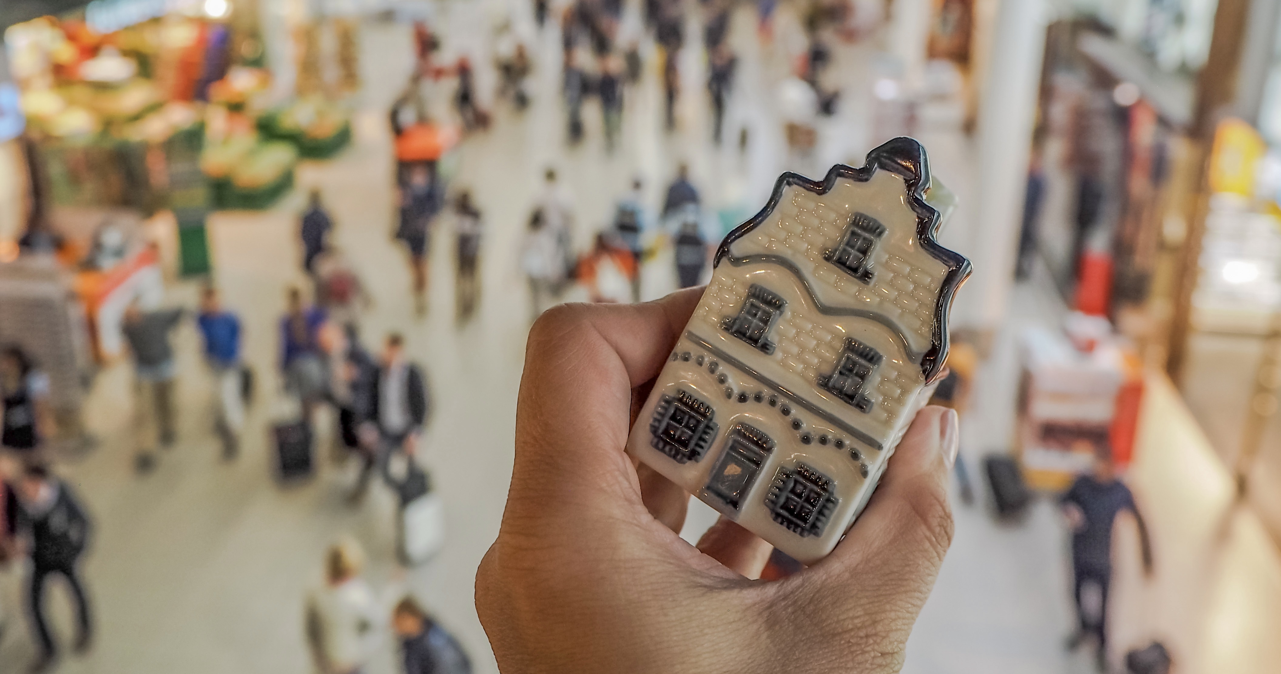 Hand holding a traditional Dutch house in Delft blue porcelain in Schiphol airport in the Netherlands