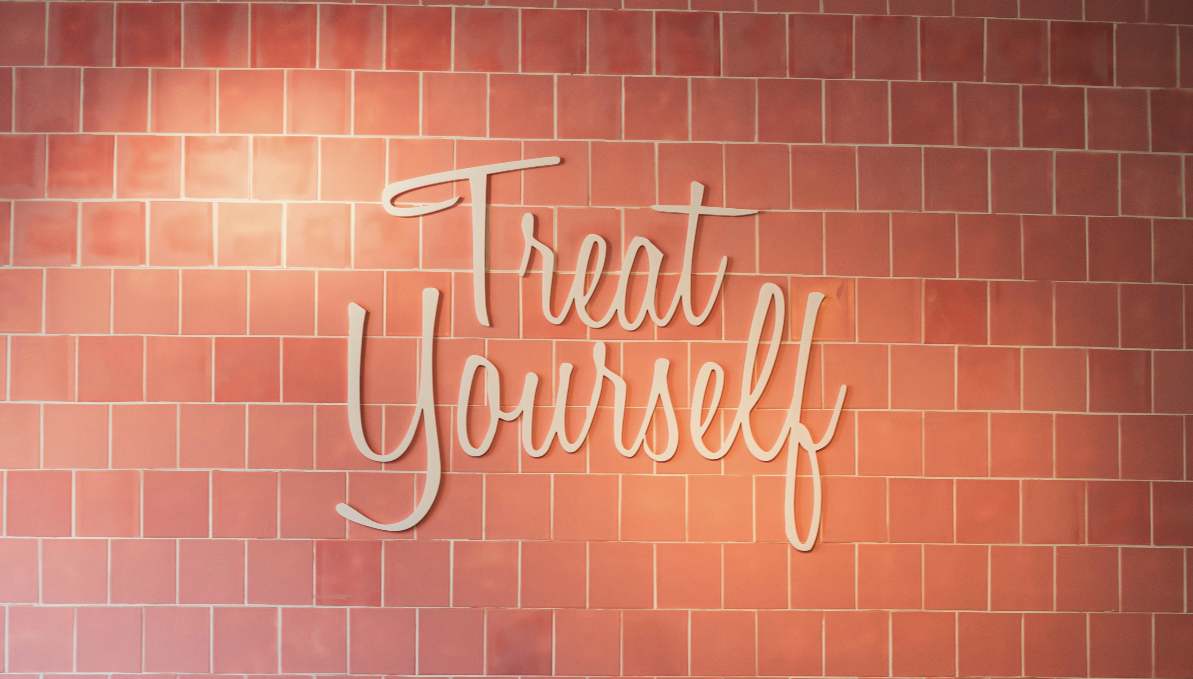 Treat Yourself sign on a pink tiled wall at Café Chloé