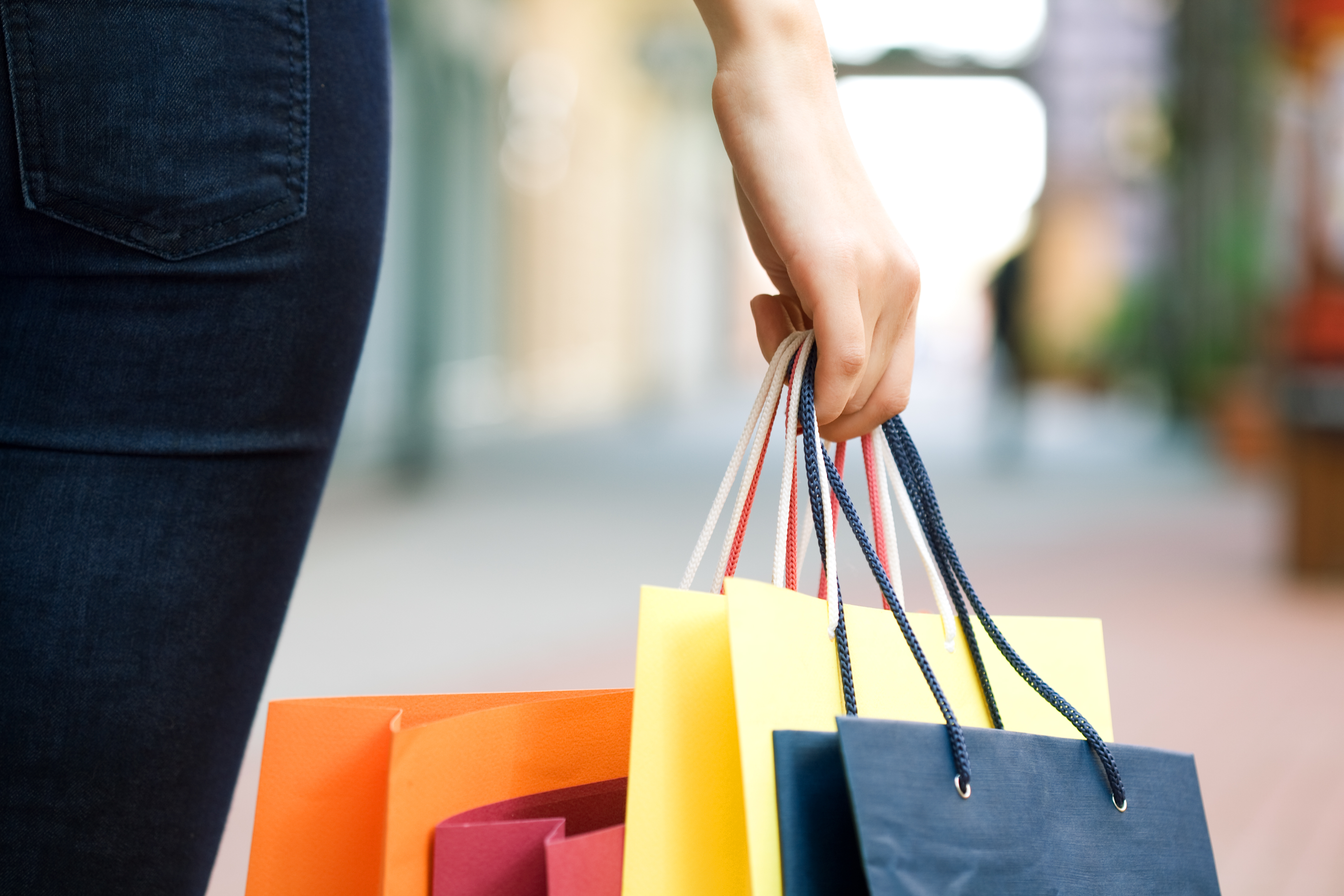 hand of young woman with multi-coloured bags with purchases