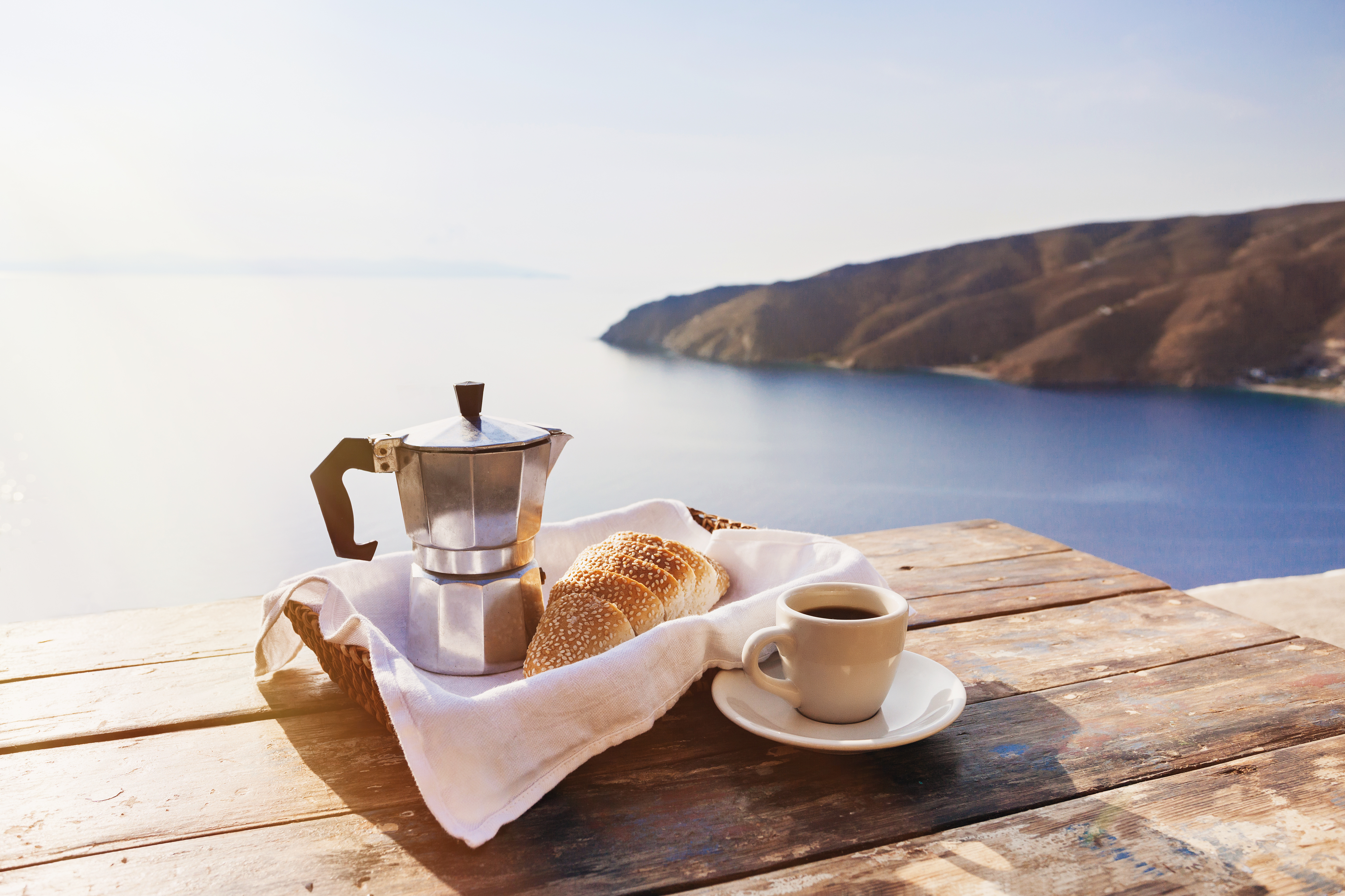 Mediterranean breakfast, cup of coffee and fresh bread on a table with beautiful sea view at the background