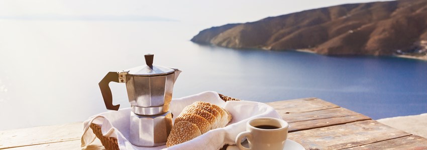 Mediterranean breakfast, cup of coffee and fresh bread on a table with beautiful sea view at the background