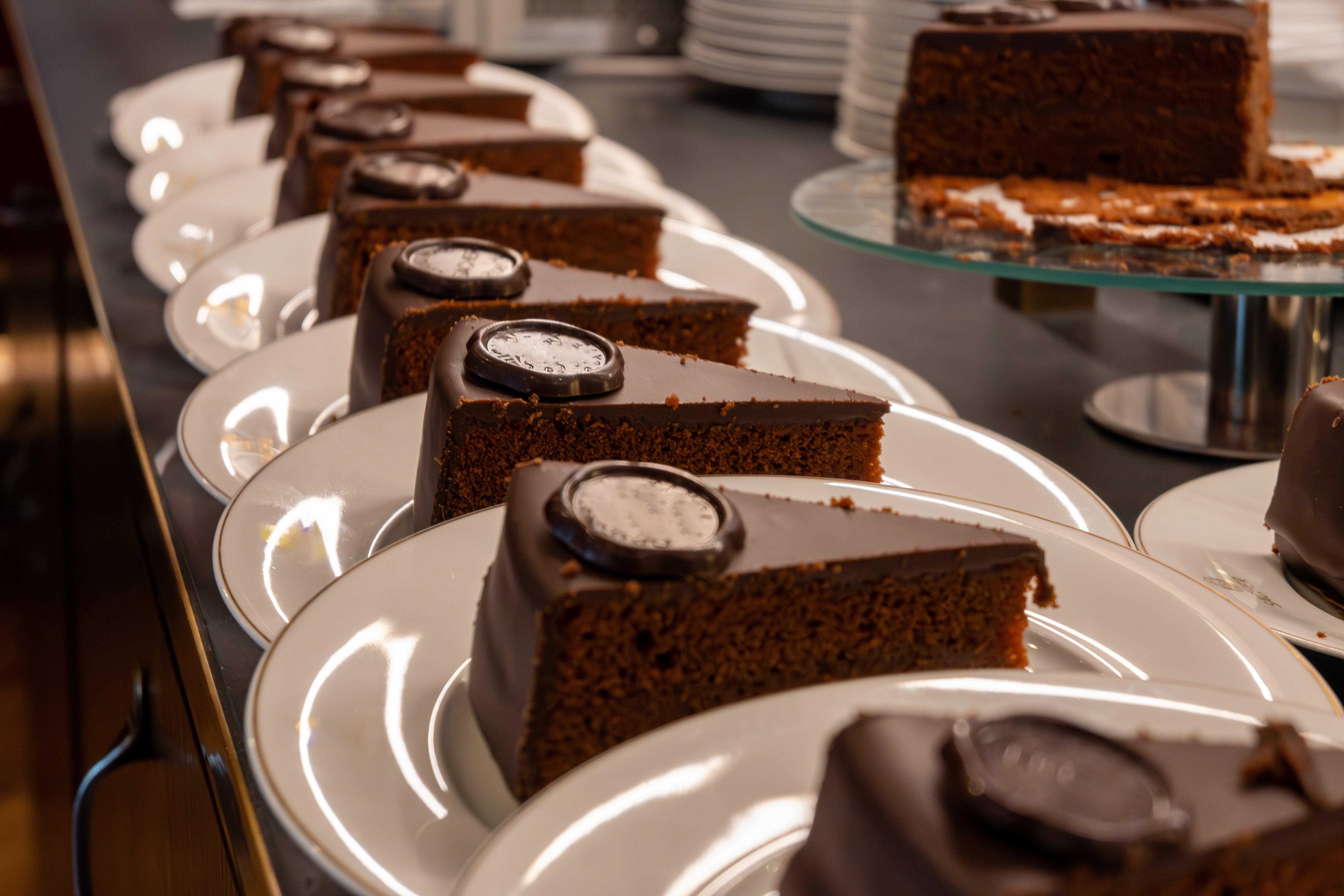 Many white plates with pieces of famous Sachertorte chocolate cake