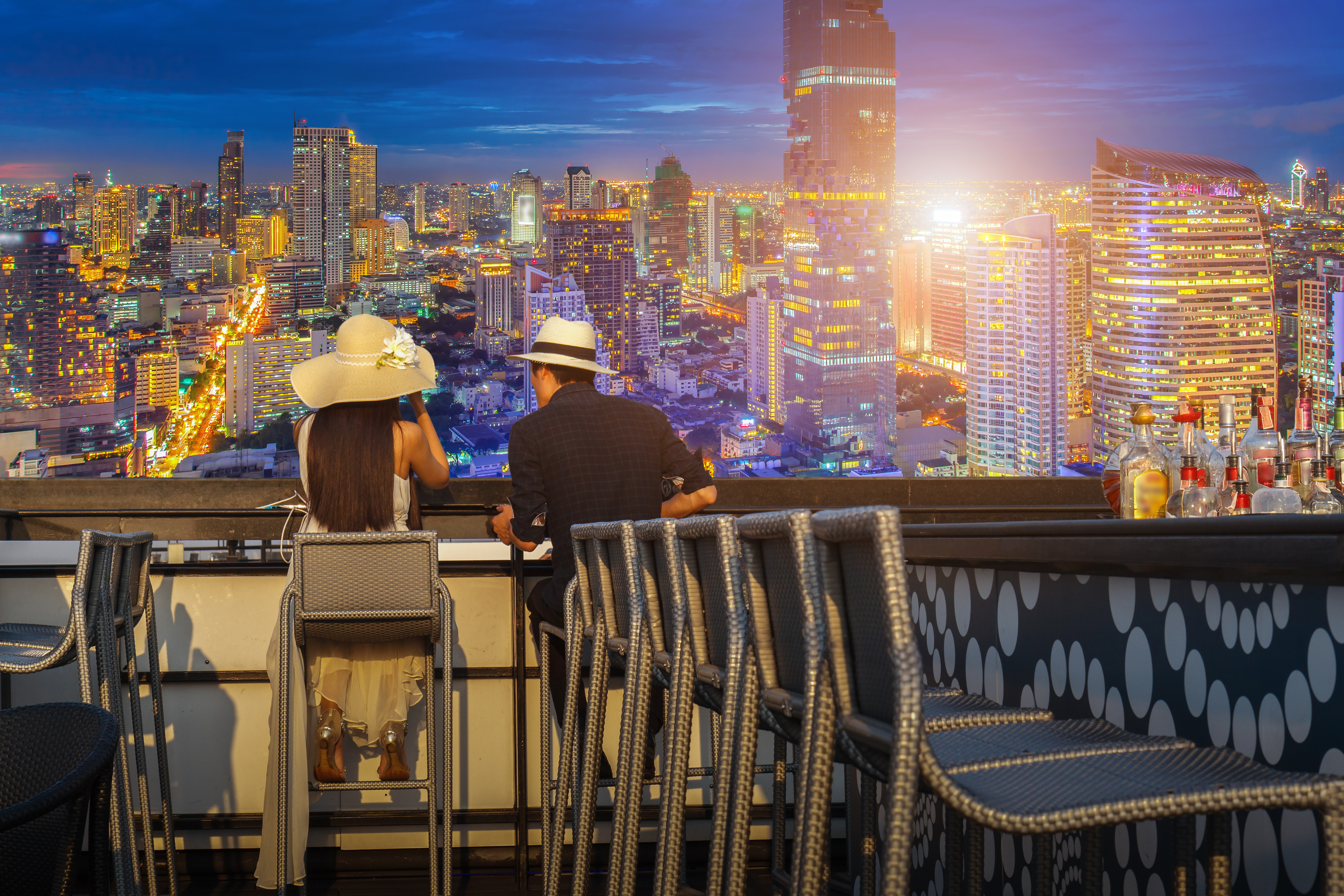 Asian lover couple enjoying look at view twilight time on top view bar and restaurant in this time beautiful colorful night at Bangkok City