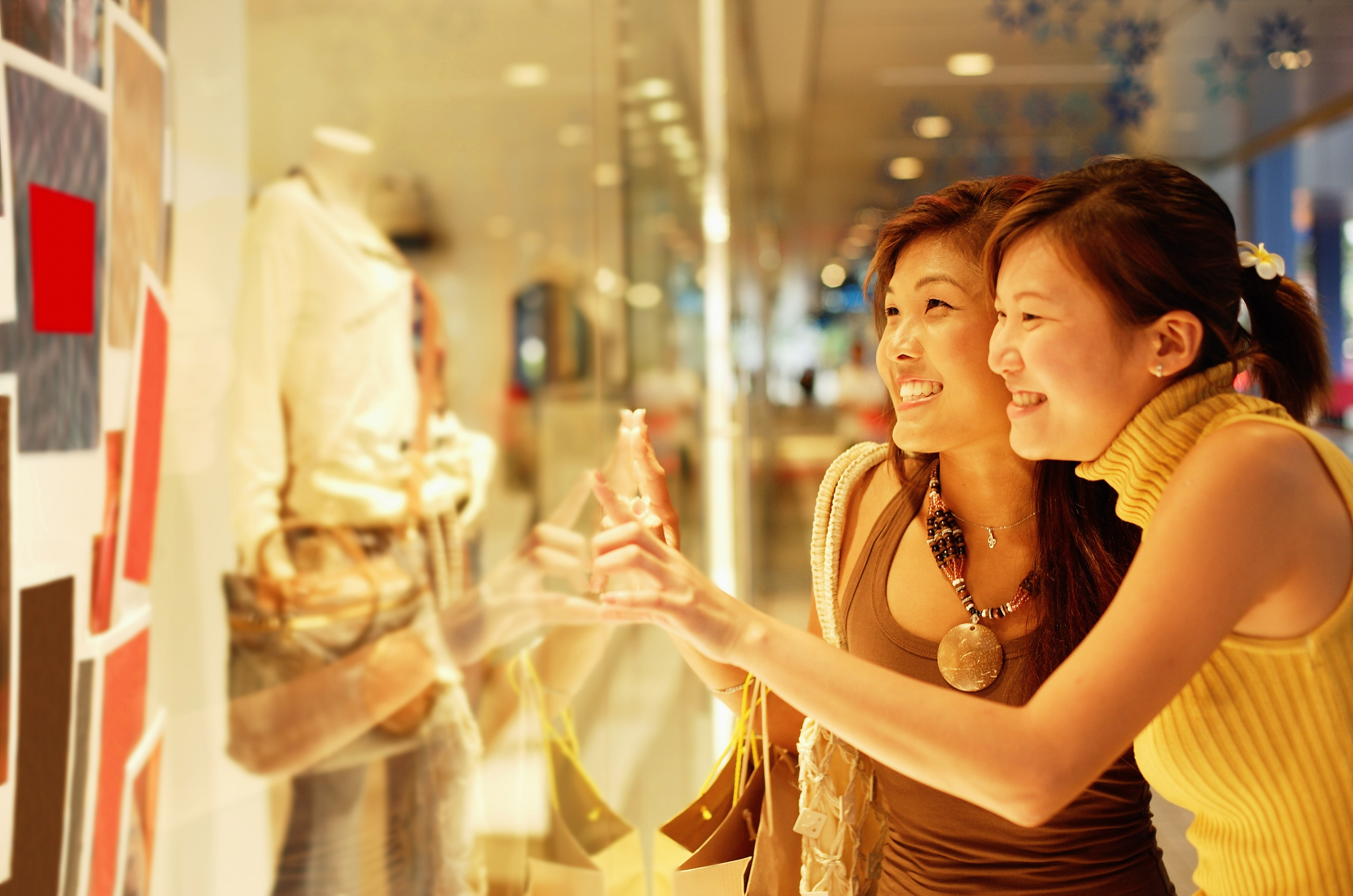 Young women, standing outside window display, looking in