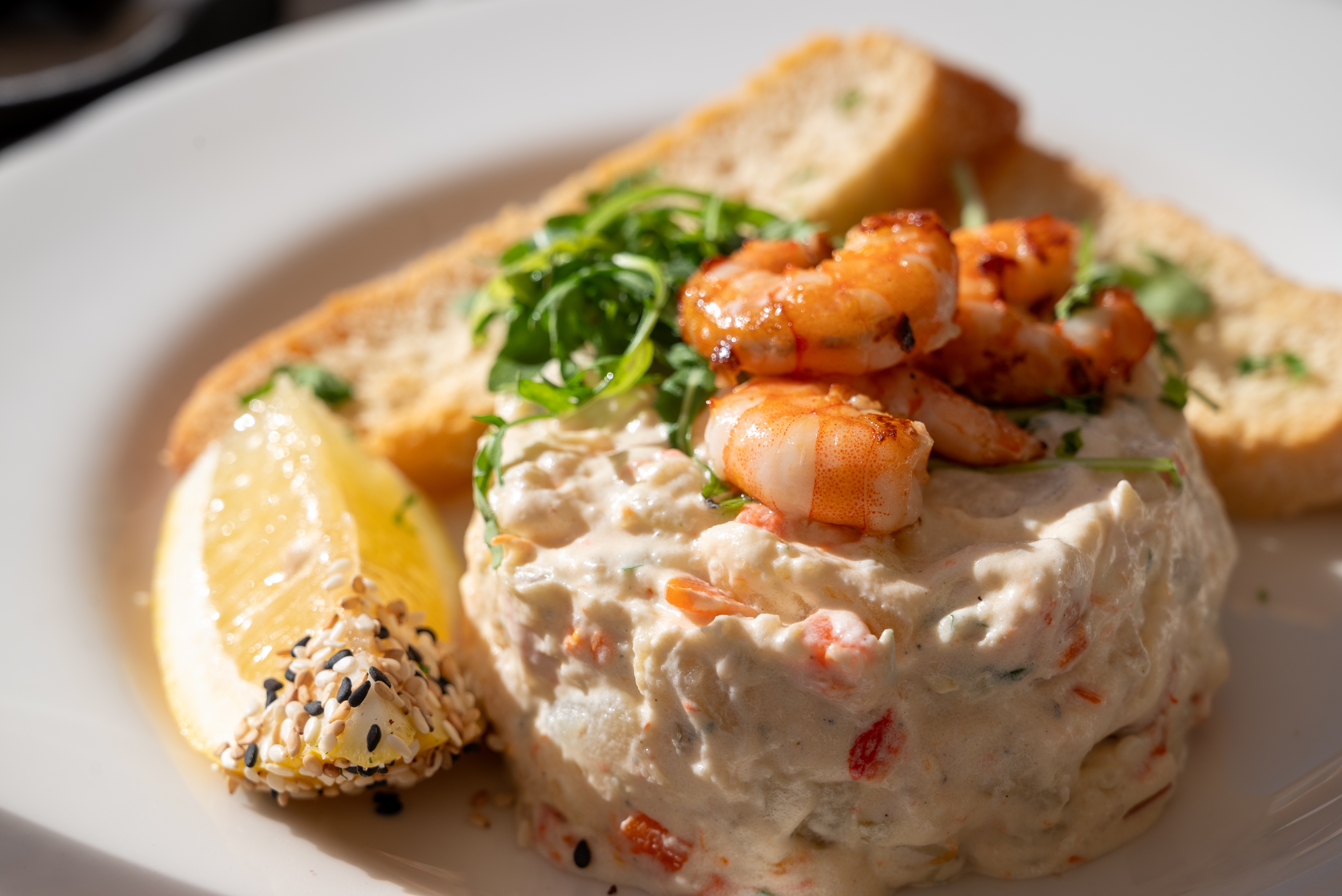 a plate of 'ensaladilla rusa' (russian salad) made of potatoes, shrimps, egg, onion and mayonnaise - a typical spanish snack or tapas