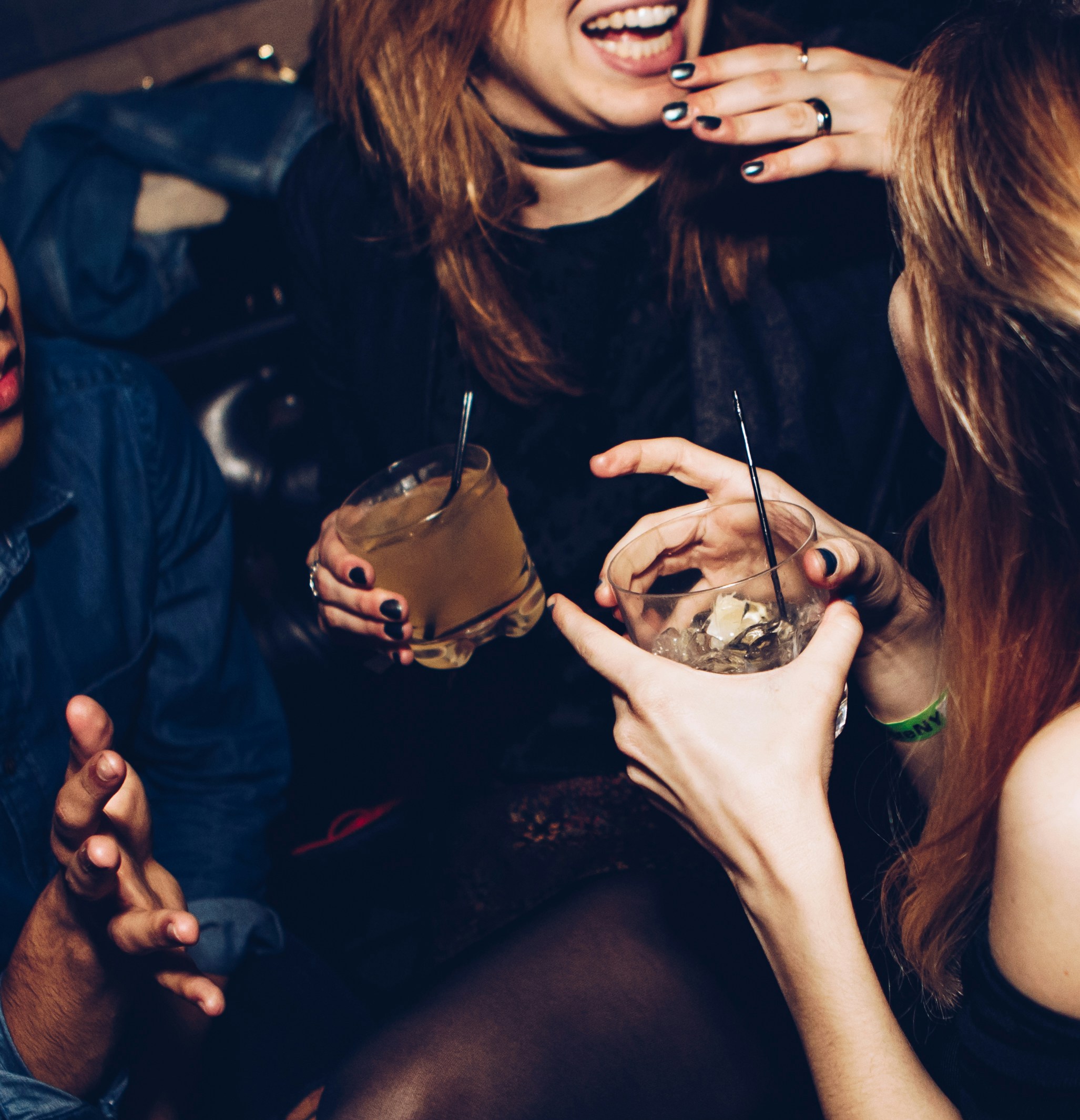 two-women-talking-while-holding-drinking-glasses at a bar