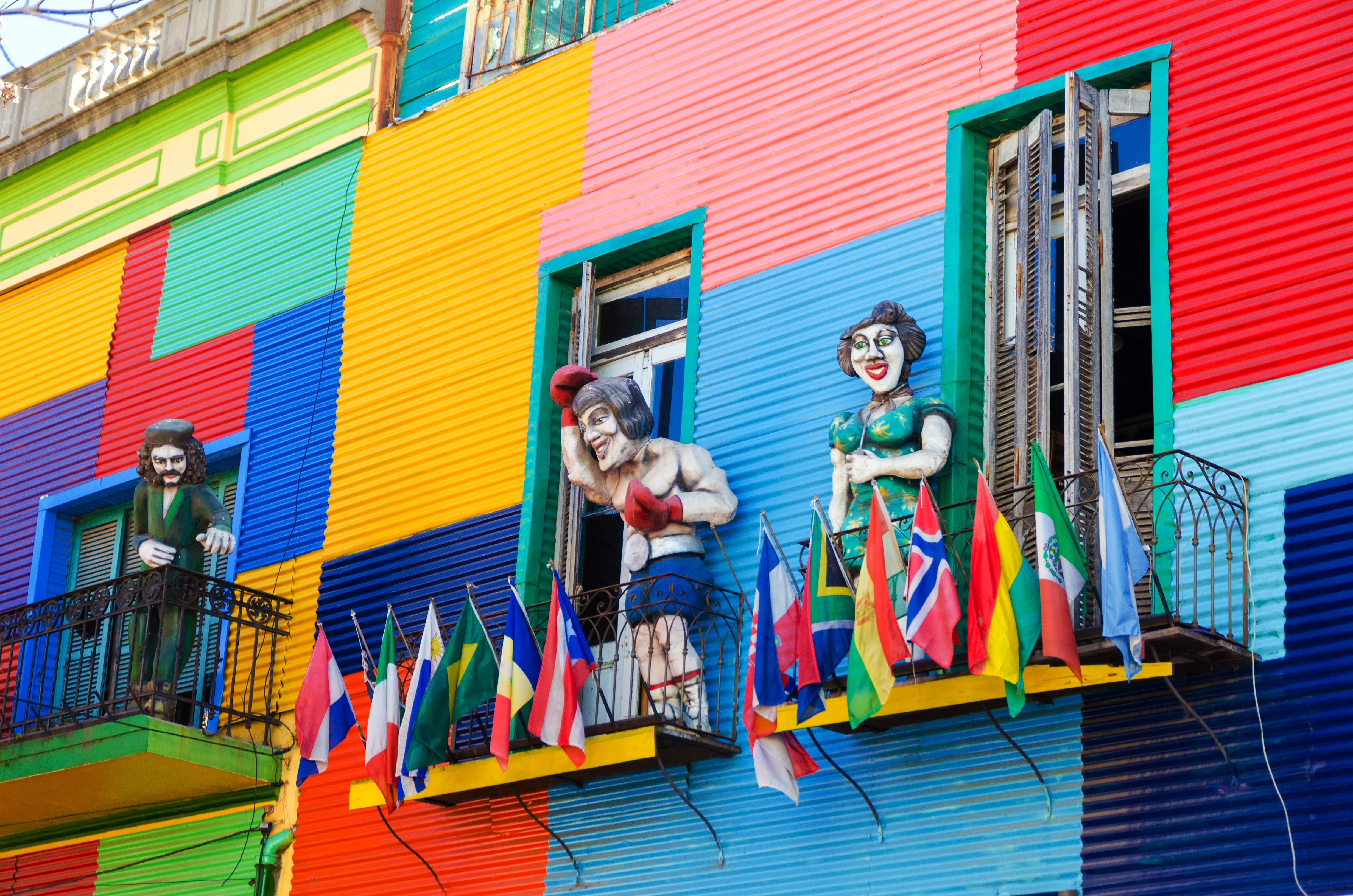 A colorful building in La Boca neighborhood of Buenos Aires with statues and flags