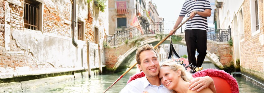 Romantic young beautiful couple sailing in venetian canal in gondola. Italy, Europe.