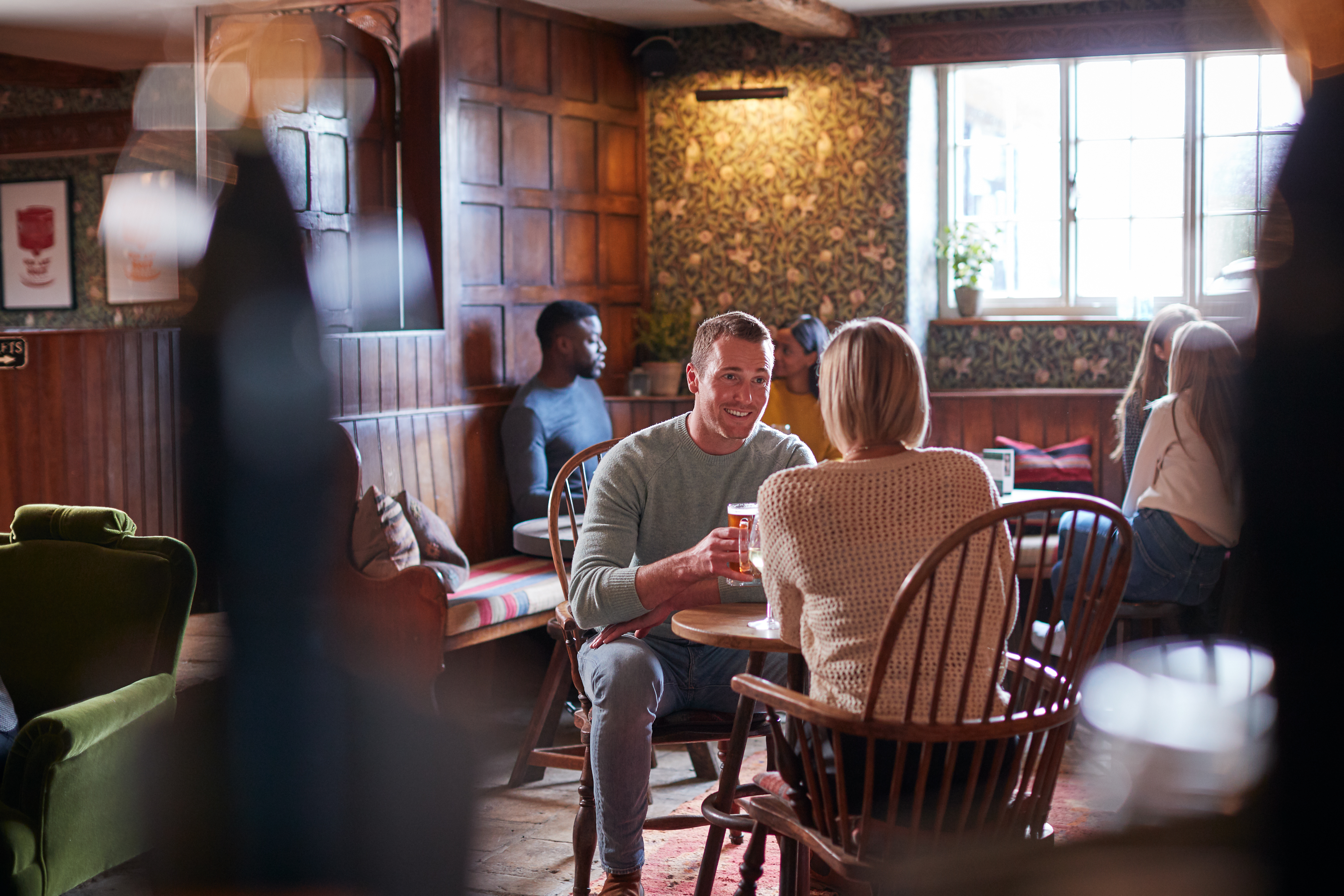 Couple Meeting For Lunchtime Drinks In Traditional English Pub Making A Toast