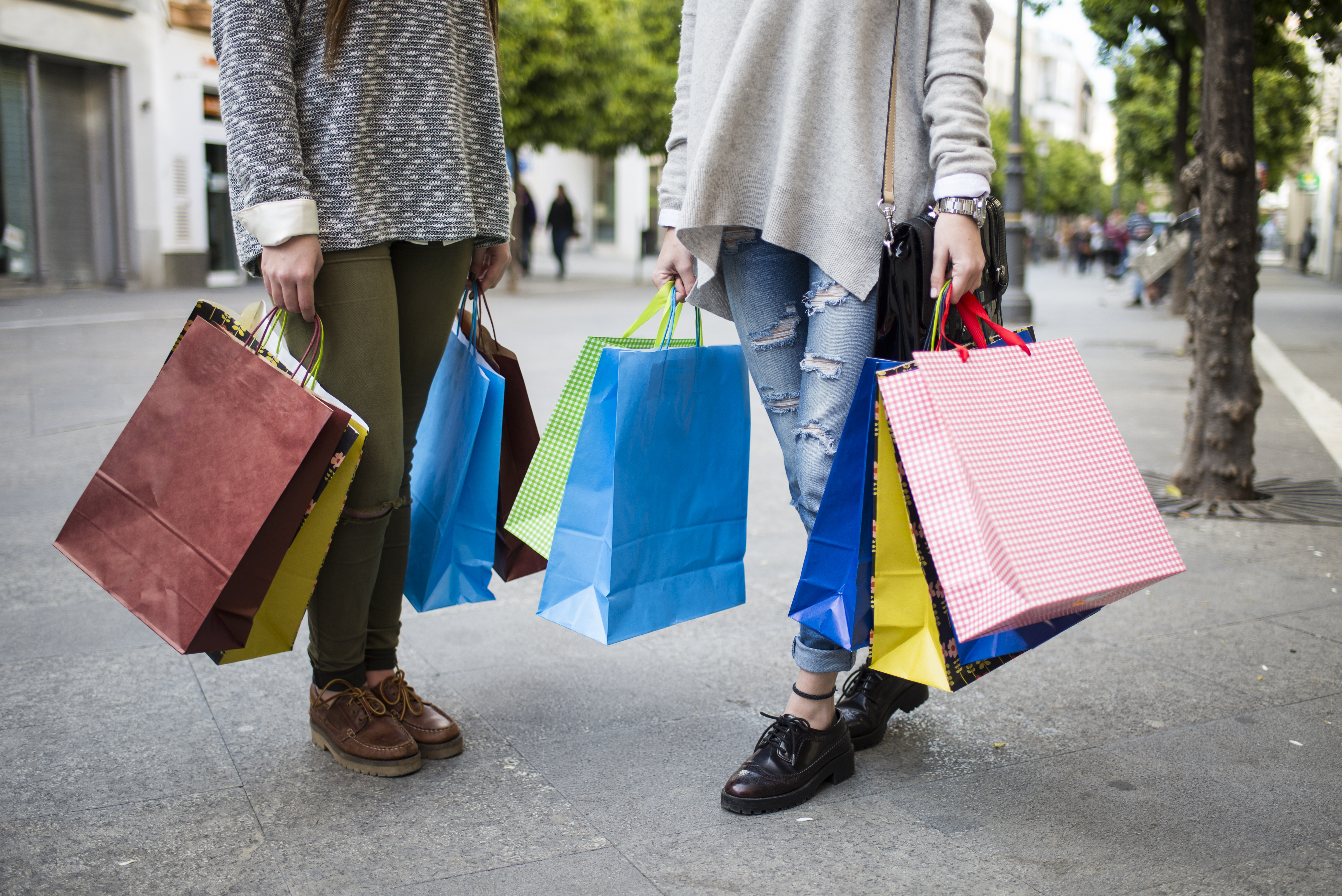 Close-up of two young women carrying shopping bags on the street.