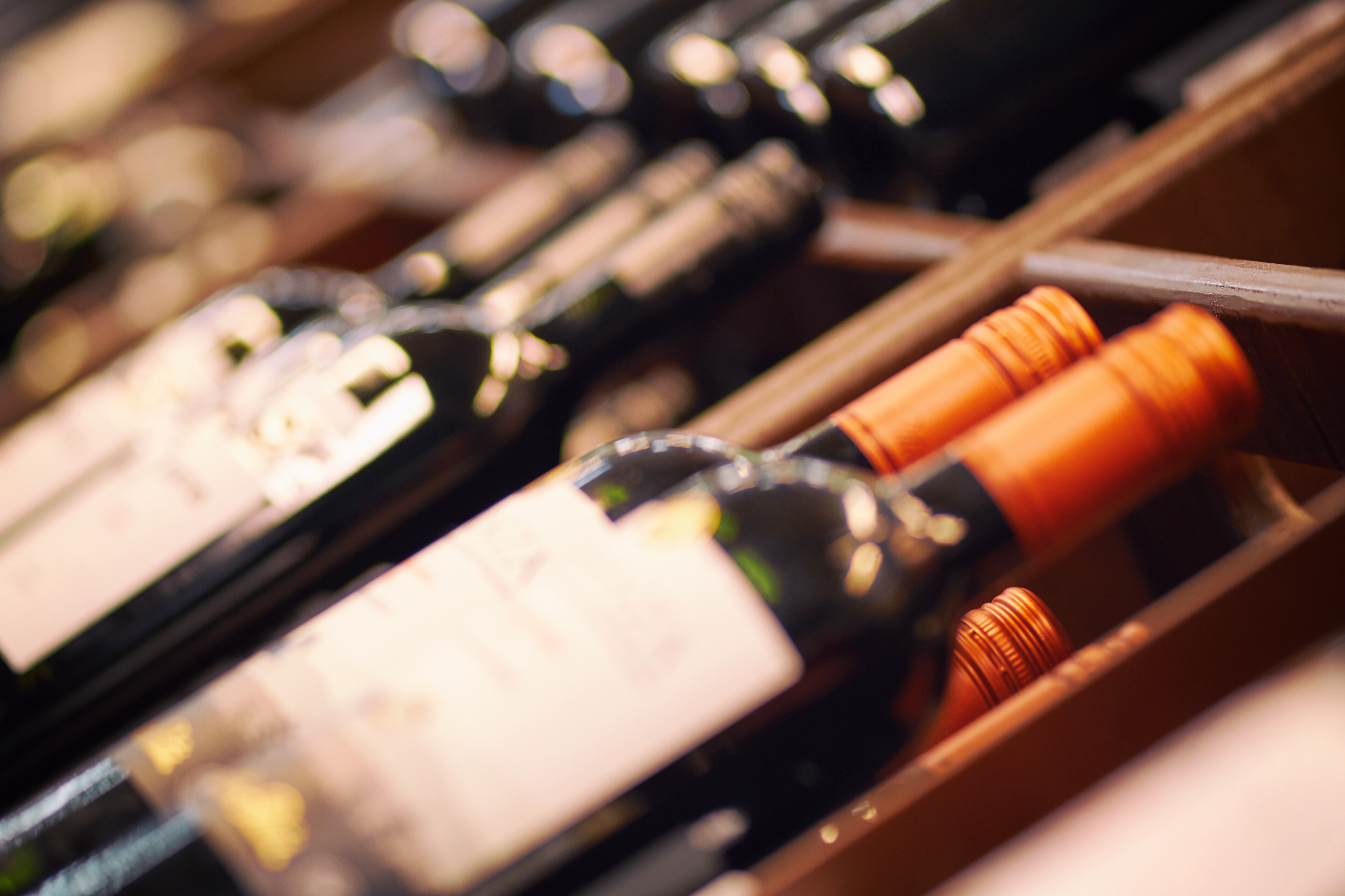 Blurred racks with bottles of red wine. Shelves with bottles of wine in a large grocery supermarket. Basic background for design
