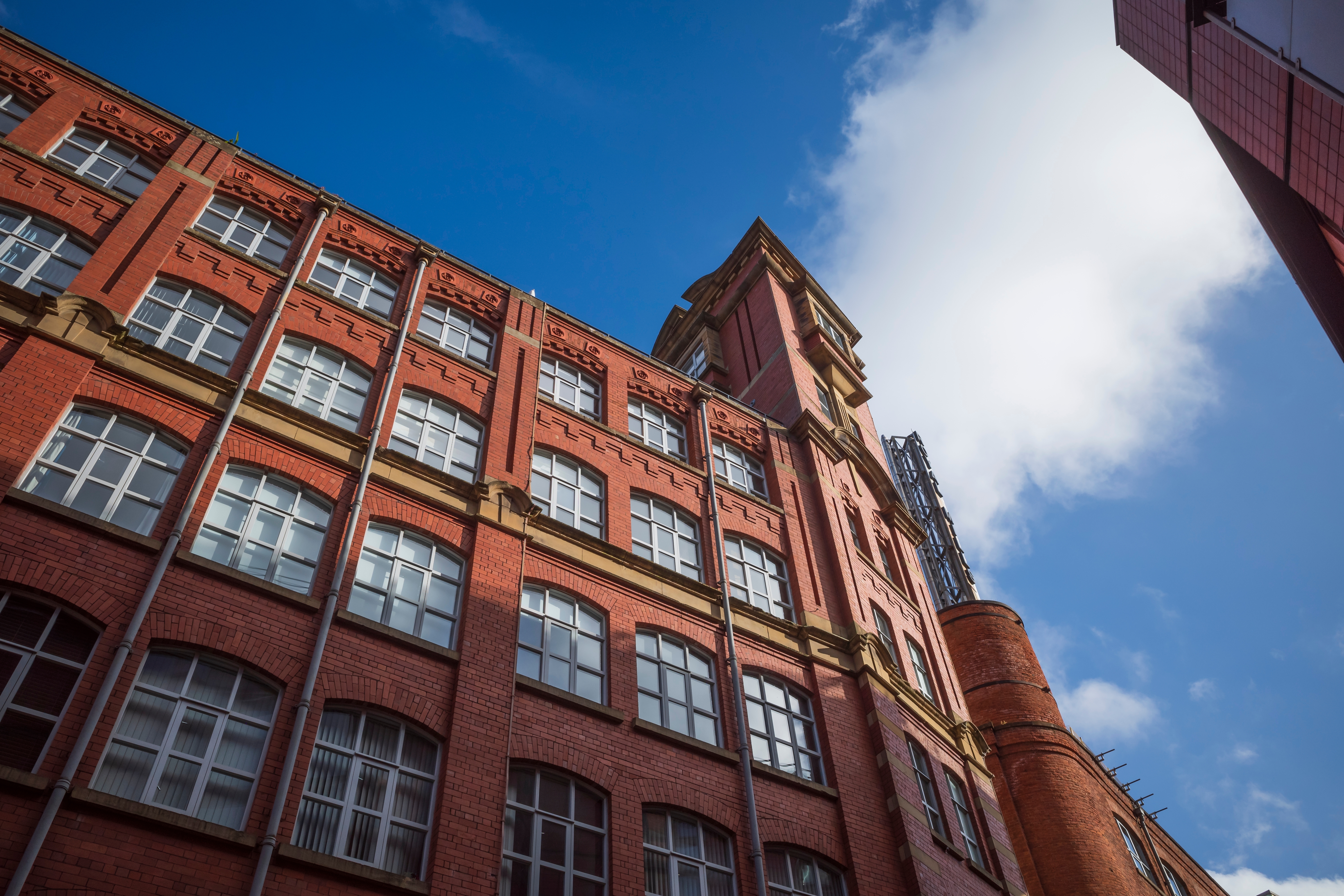 Manchester city center. Historic red brick building under a clear blue sky and fluffy clouds