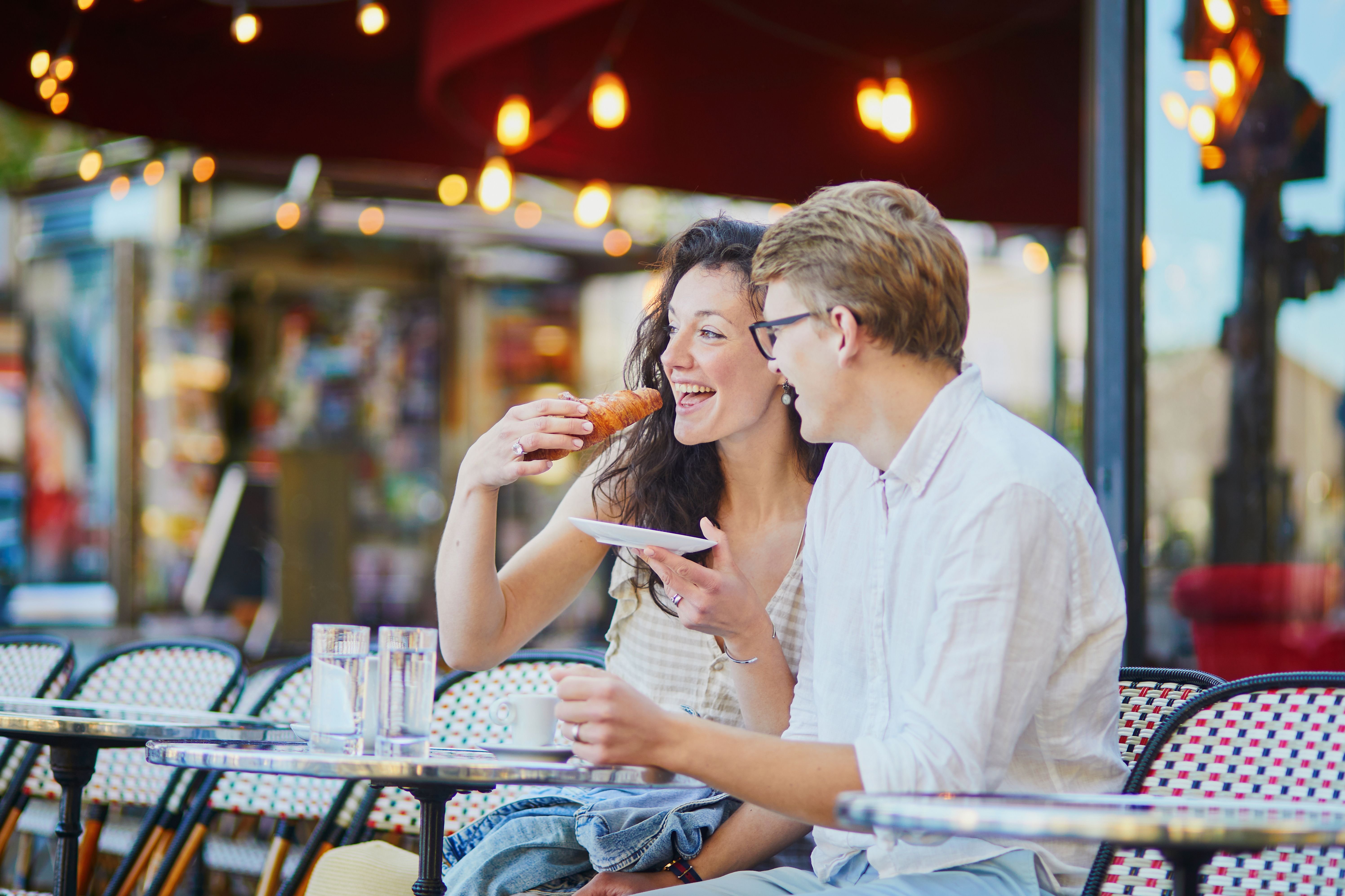 Happy romantic couple in Paris, drinking coffee in traditional Parisian outdoor cafe. Tourists spending their vacation in France
